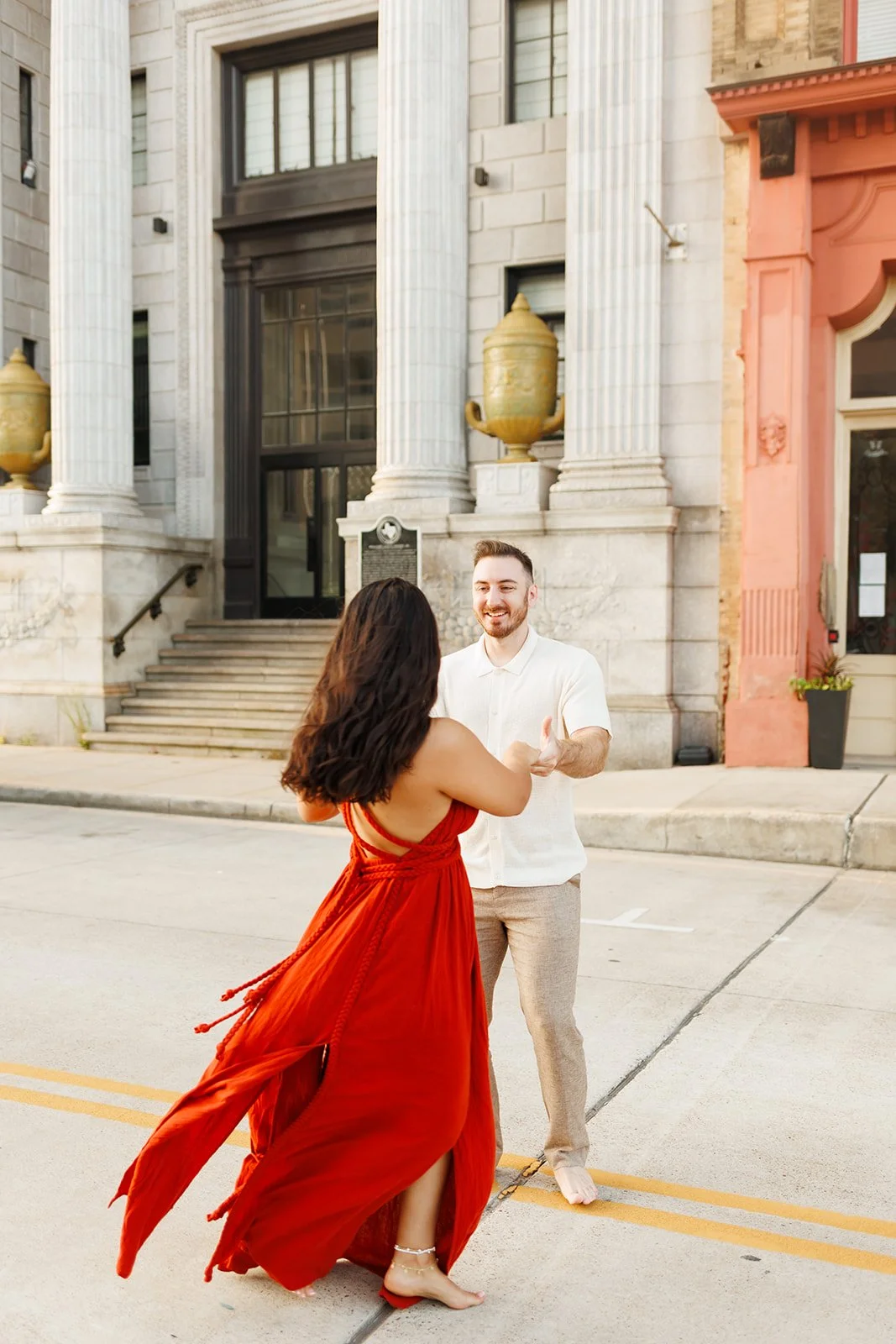 Carefree Houston engagement moment with a couple dancing barefoot on a city street in front of a historic building — Wild Ivy Creative.