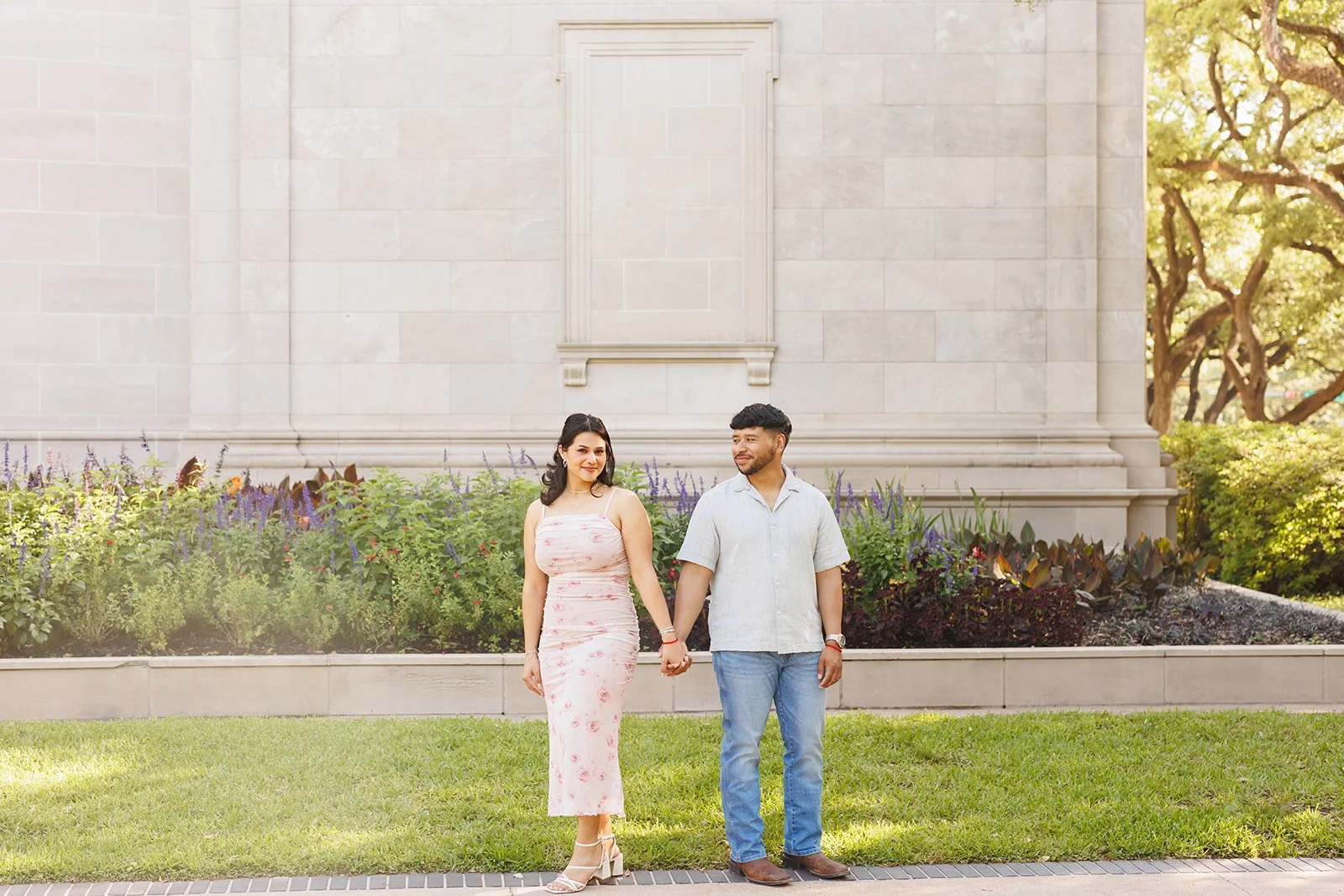Romantic Houston engagement photo after surprise proposal in front of a stone-walled Fine Art Museum with purple garden blooms — Wild Ivy Creative.
