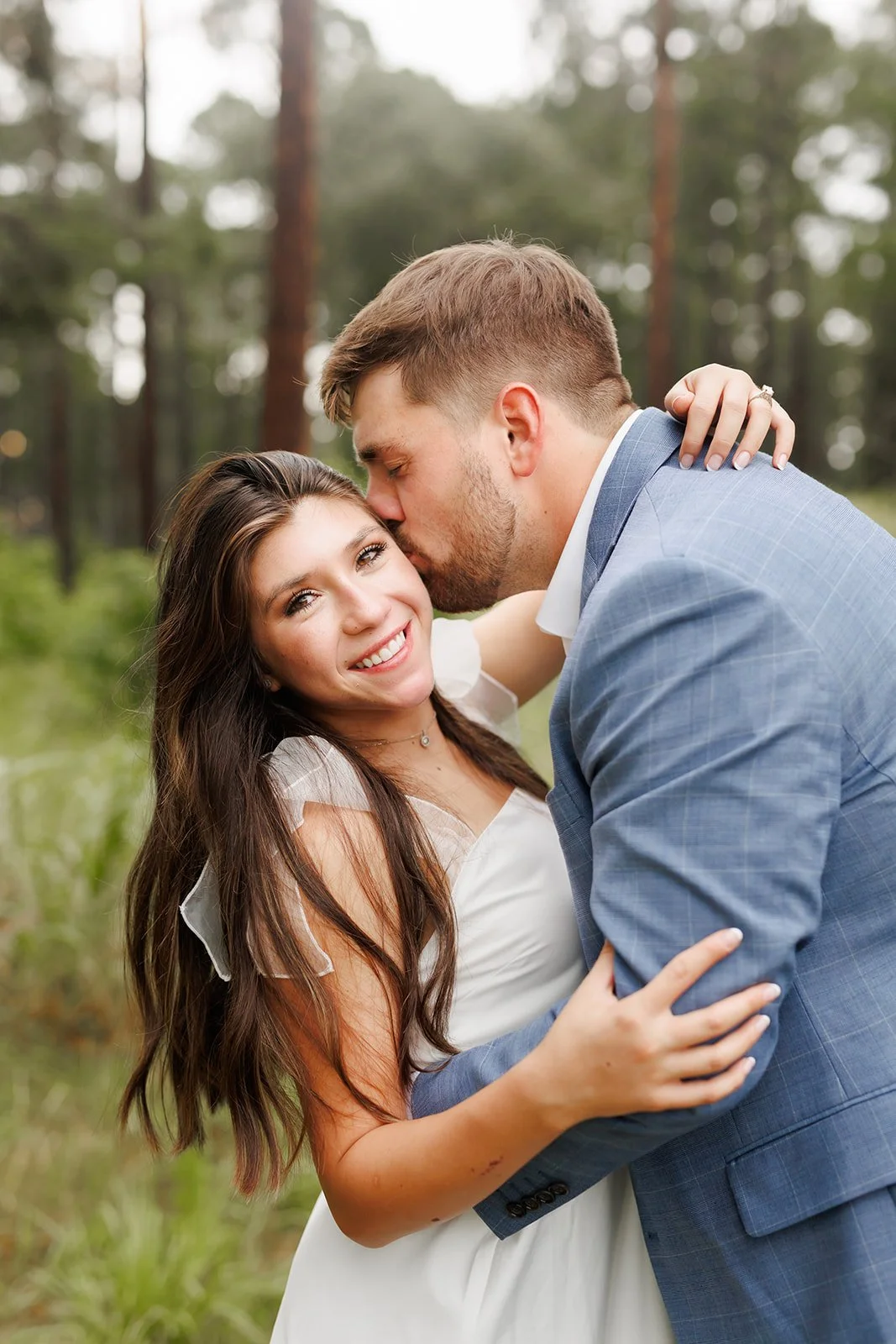 WG Jones engagement session in The Woodlands, TX with a couple sharing a kiss — woman in a white dress and man in a navy suit, by Wild Ivy Creative.