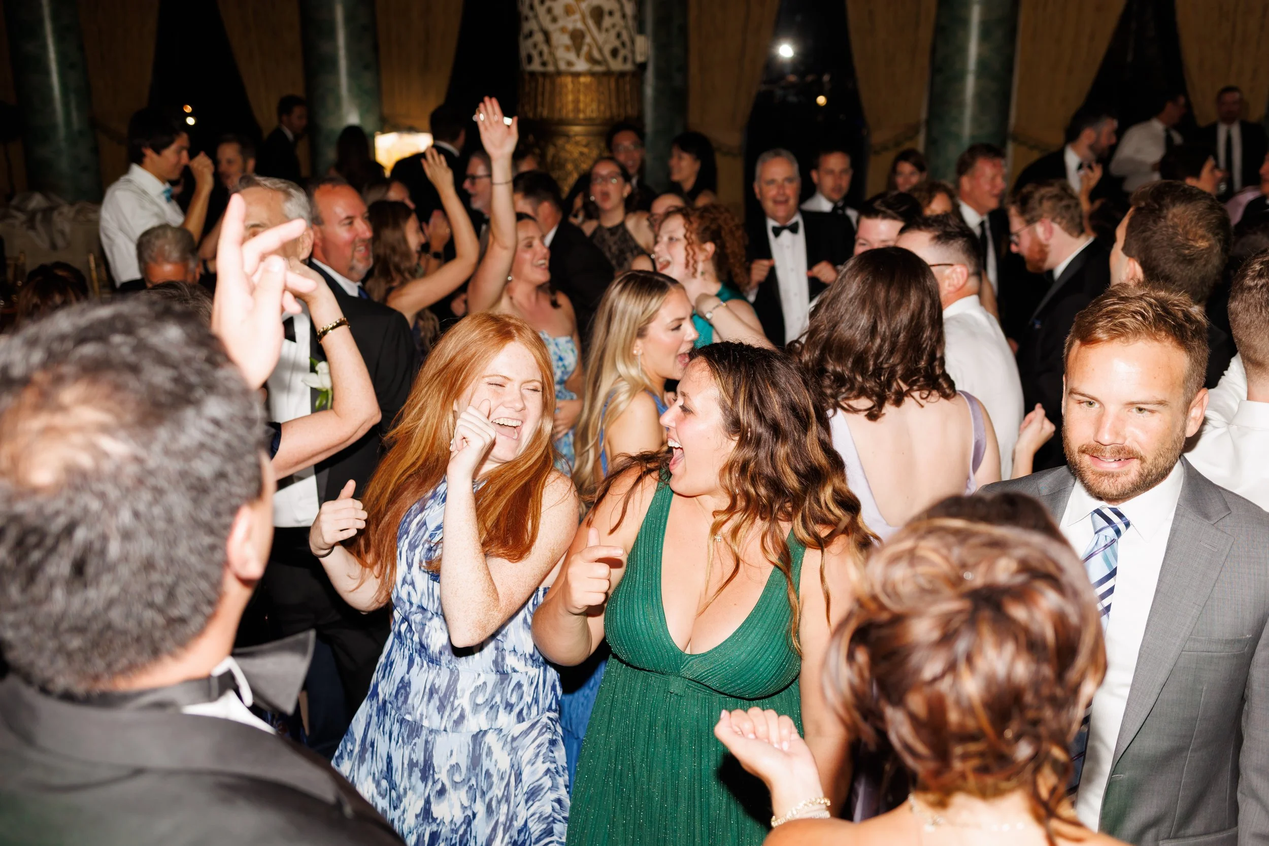 Guests dancing and celebrating at a Houston wedding reception with joyful expressions, formal attire, and elegant uplighting, capturing candid moments of laughter and connection.