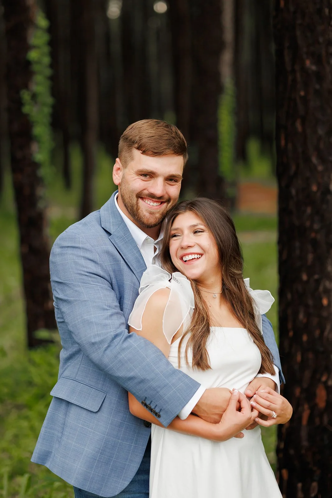 Natural light engagement session in a wooded area at WG Jones State Park featuring a smiling couple embracing during a Wild Ivy Creative shoot.