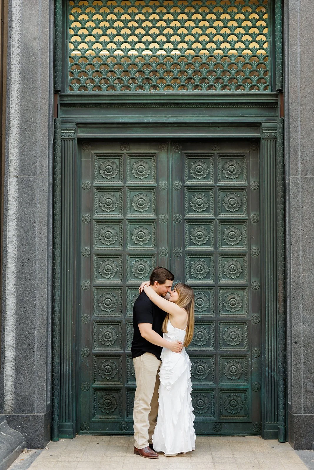 Intimate engagement photo in front of a decorative green door in Downtown Houston — a couple shares a romantic moment, captured by Wild Ivy Creative.
