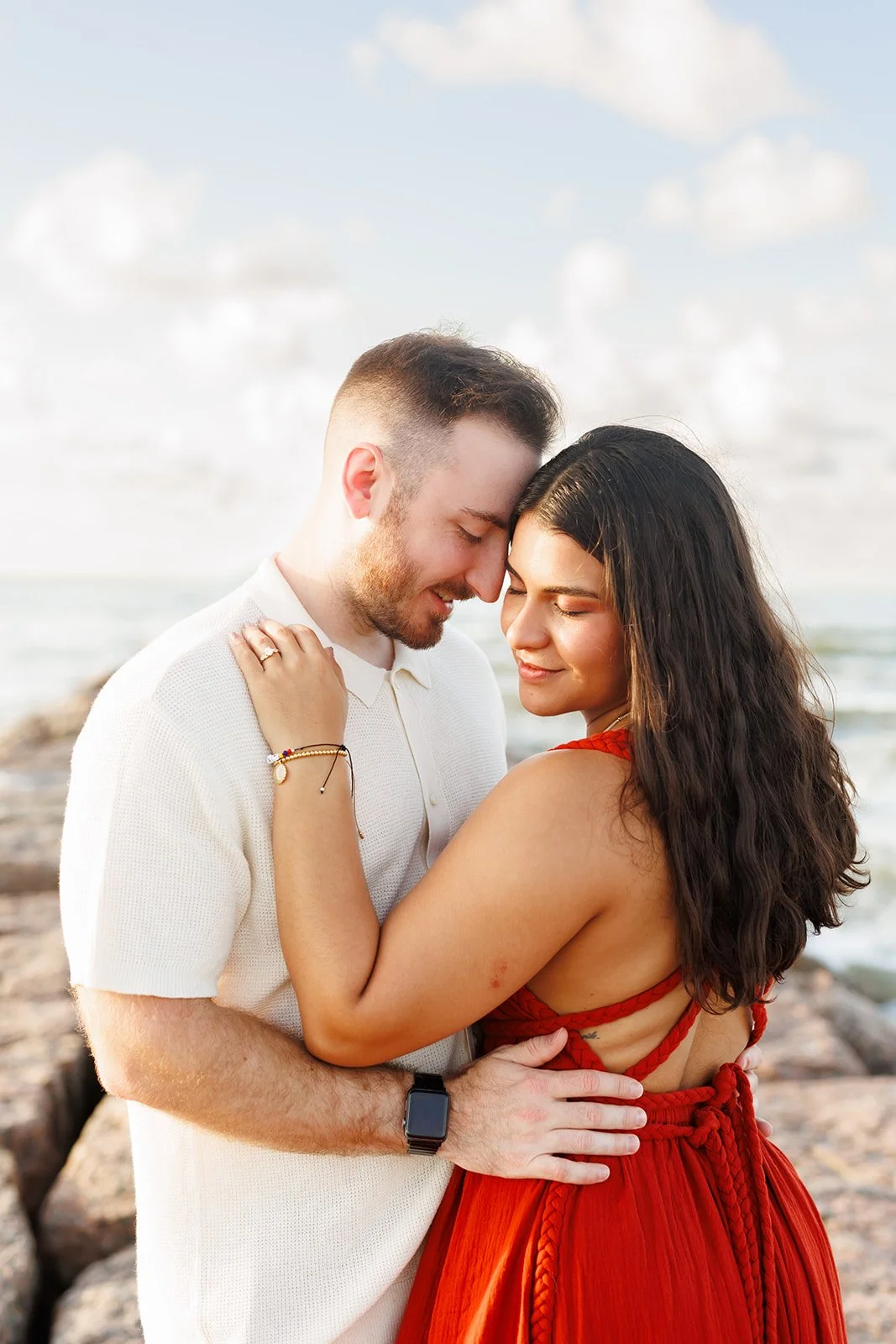 Intimate Galveston beach engagement moment — couple embracing with closed eyes and soft smiles as ocean waves roll behind them — Wild Ivy Creative.