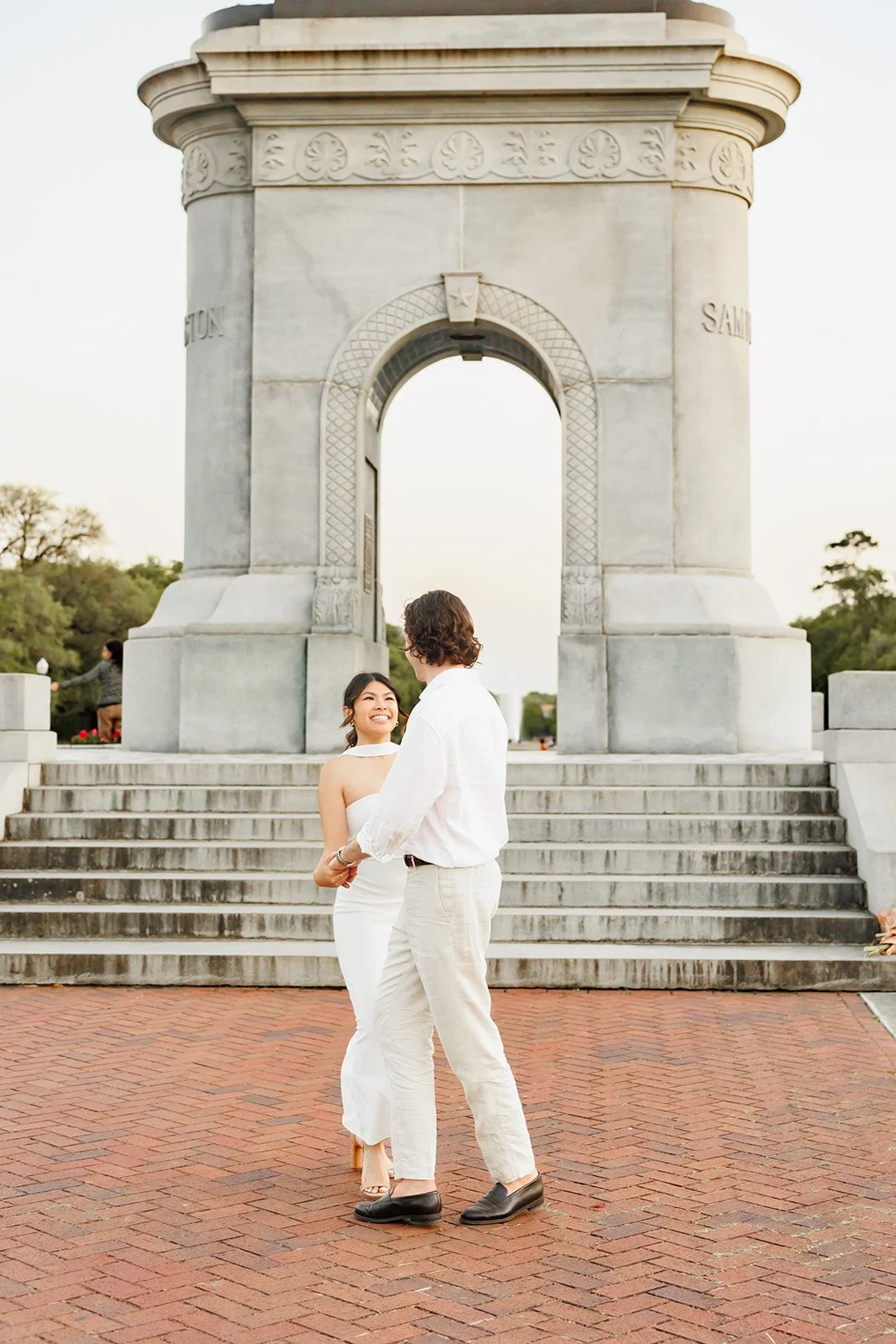 A couple dancing outdoors in front of a large stone monument with steps, during sunset.