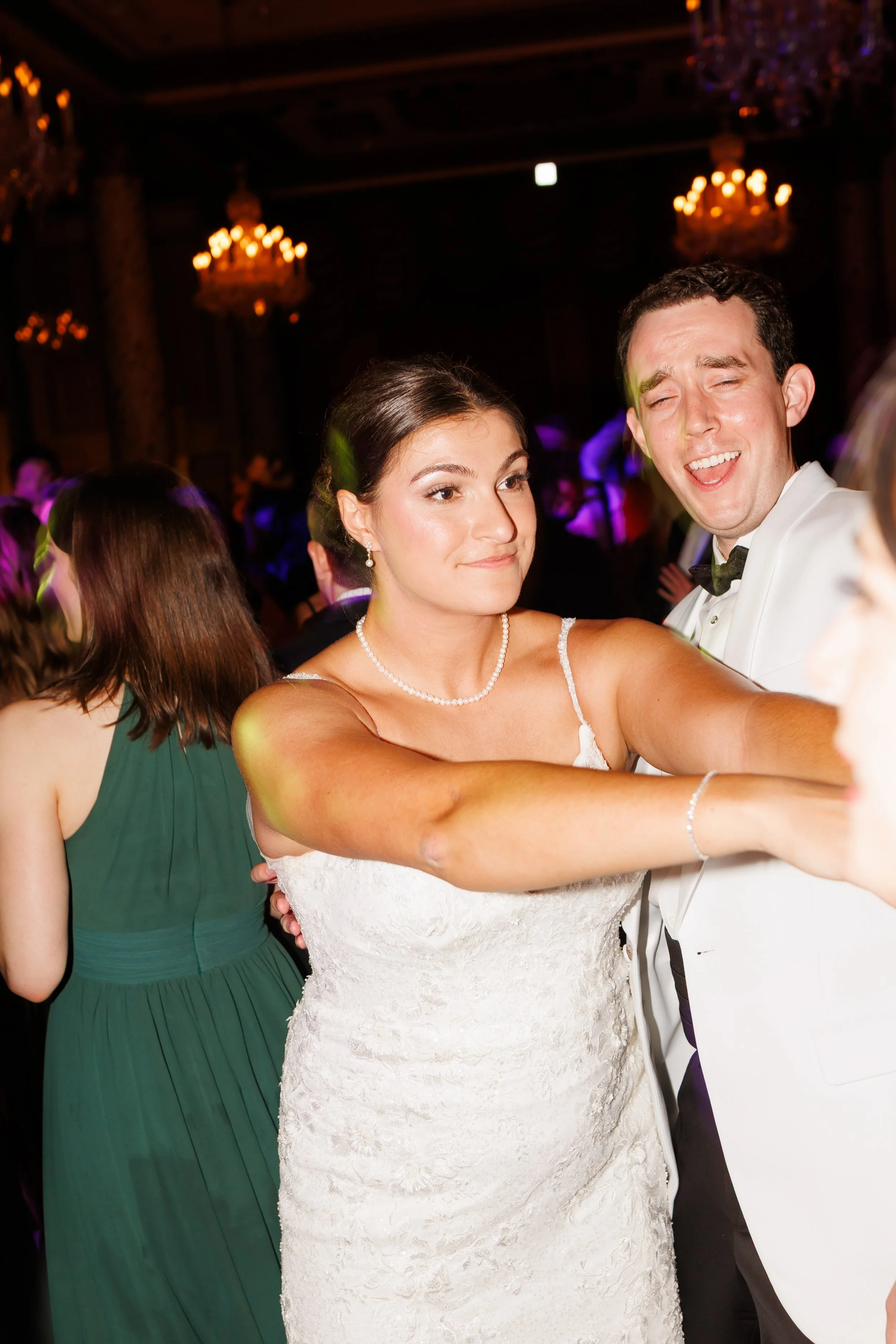 Bride and groom sharing their first dance in a luxury Houston ballroom with soft ambient lighting, sparkling chandeliers, and guests watching in the background.