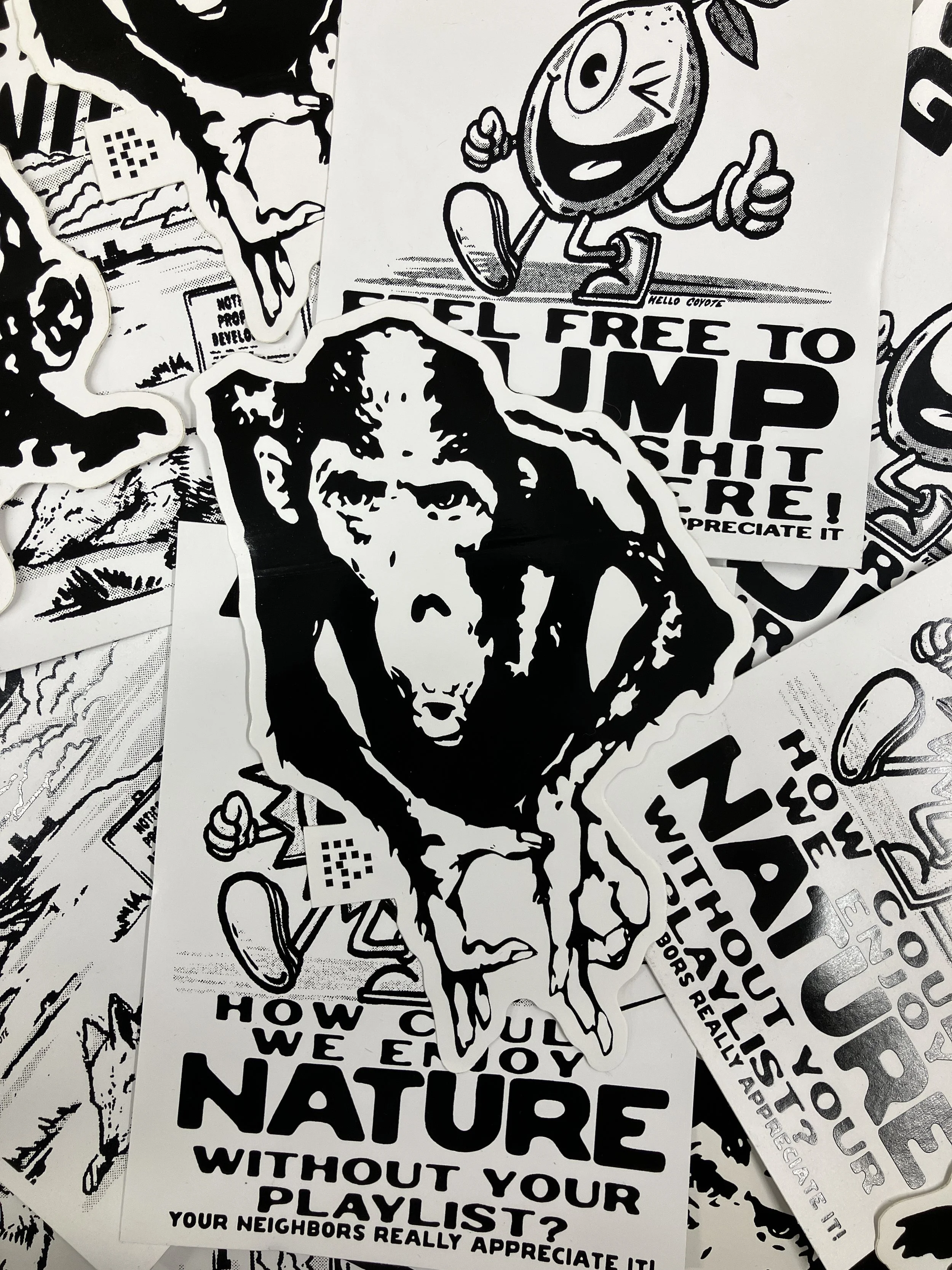 A collection of black and white stickers featuring various designs, including a chimp drawing, a cartoon character with a thumbs-up, and text-based stickers with messages about nature and protesting.