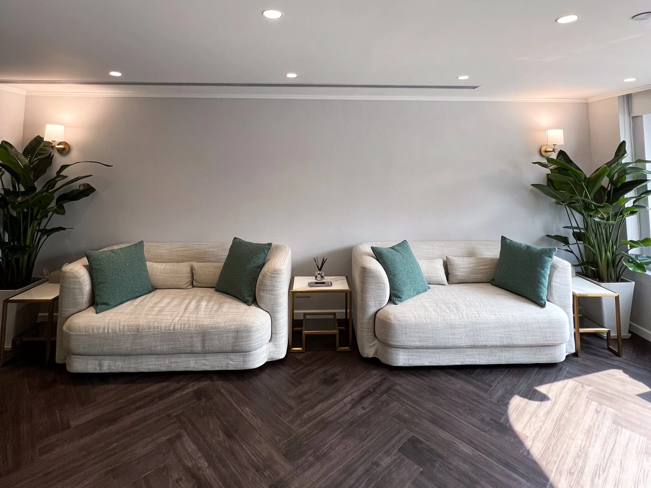 Lounge area of Alluna Medical in Hong Kong with white sofas and green cushions