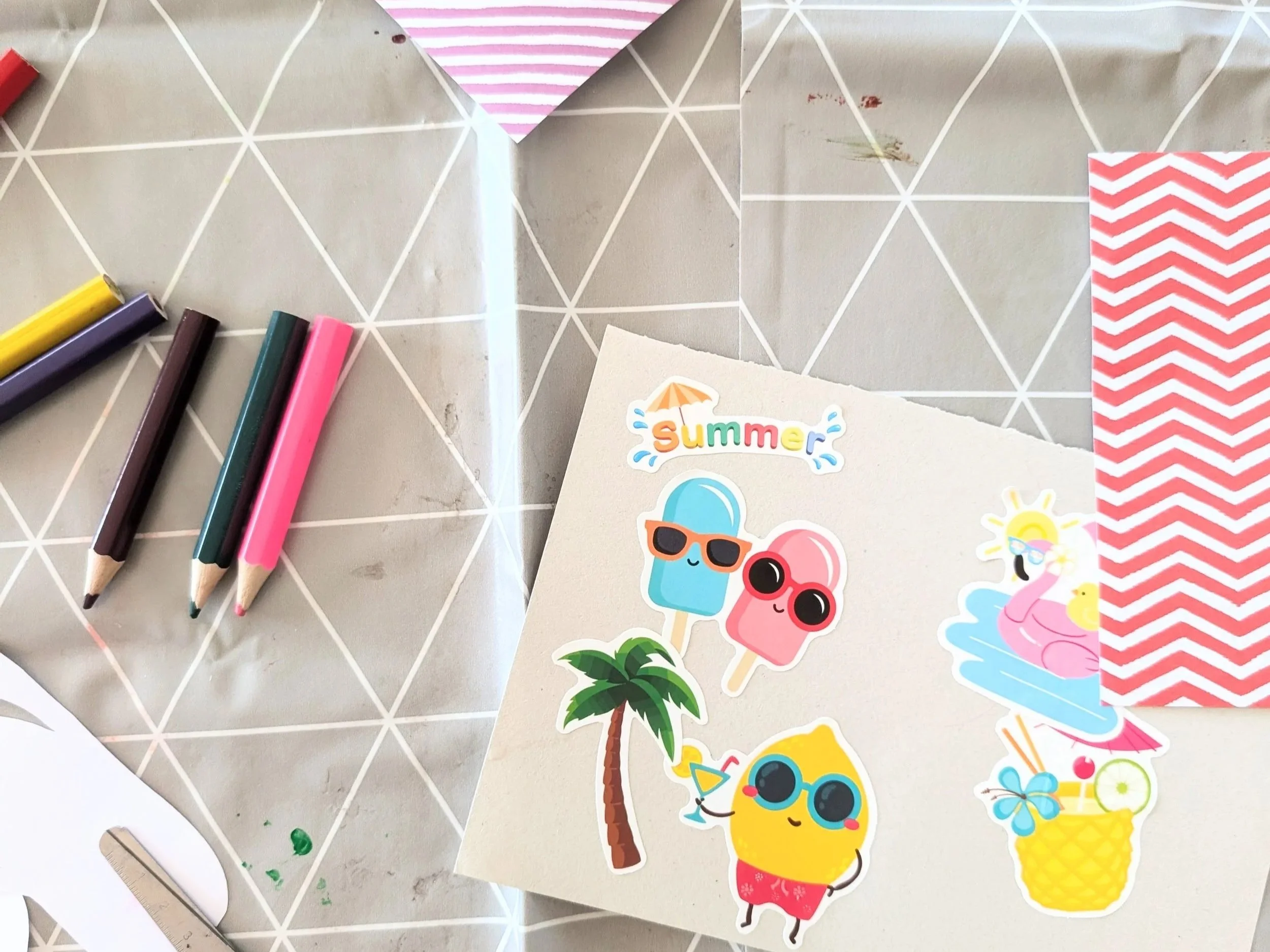 Colouring pencils, stickers and coloured paper. Scattered across a craft table.