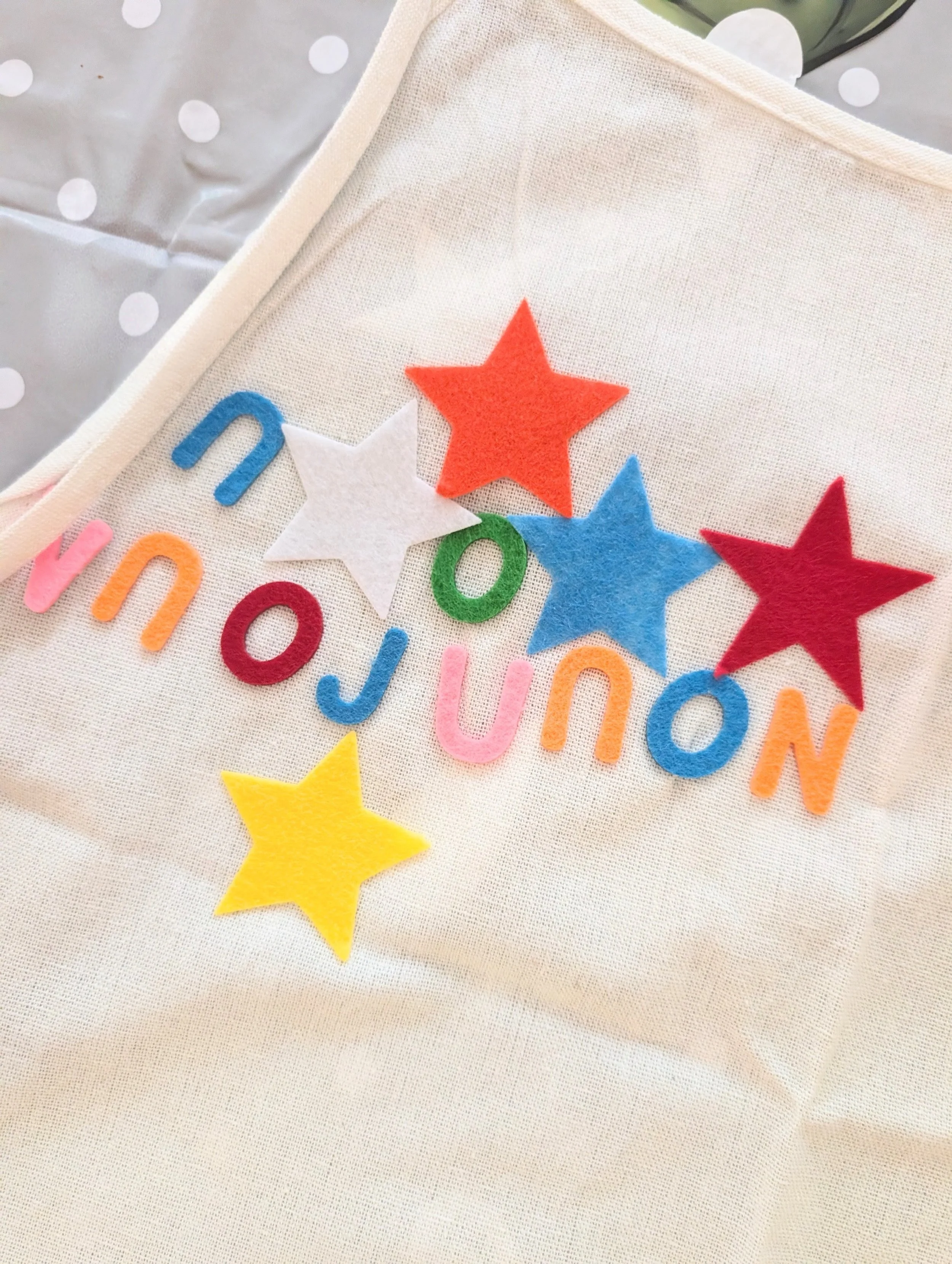 A collection of felt stars and letters, applied to a fabric cape at a craft party.