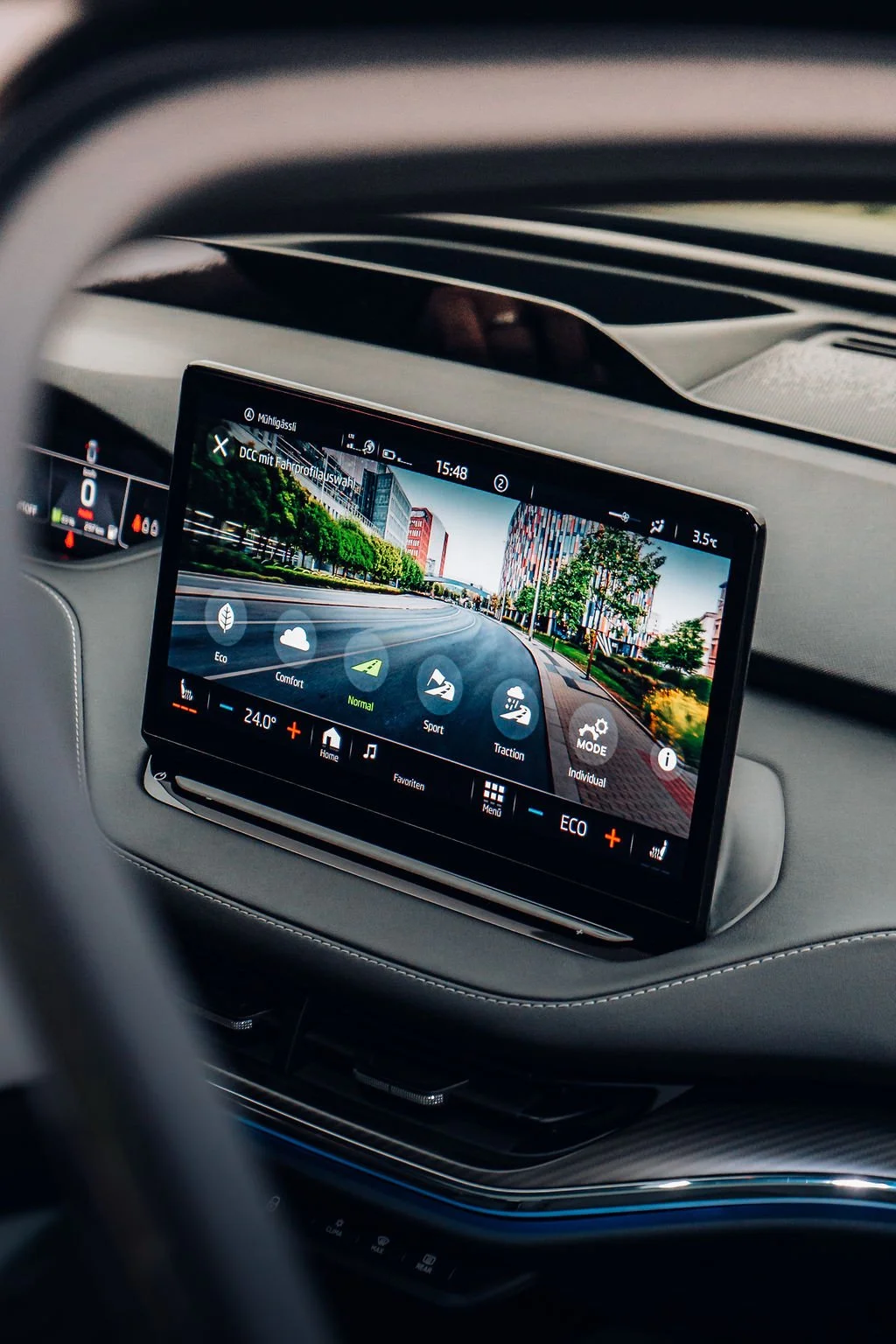 Innenaufnahme eines Fahrzeuginnenraums mit einem digitalen Display, das eine Stadtkulisse und verschiedene Fahrzeugmodi zeigt.