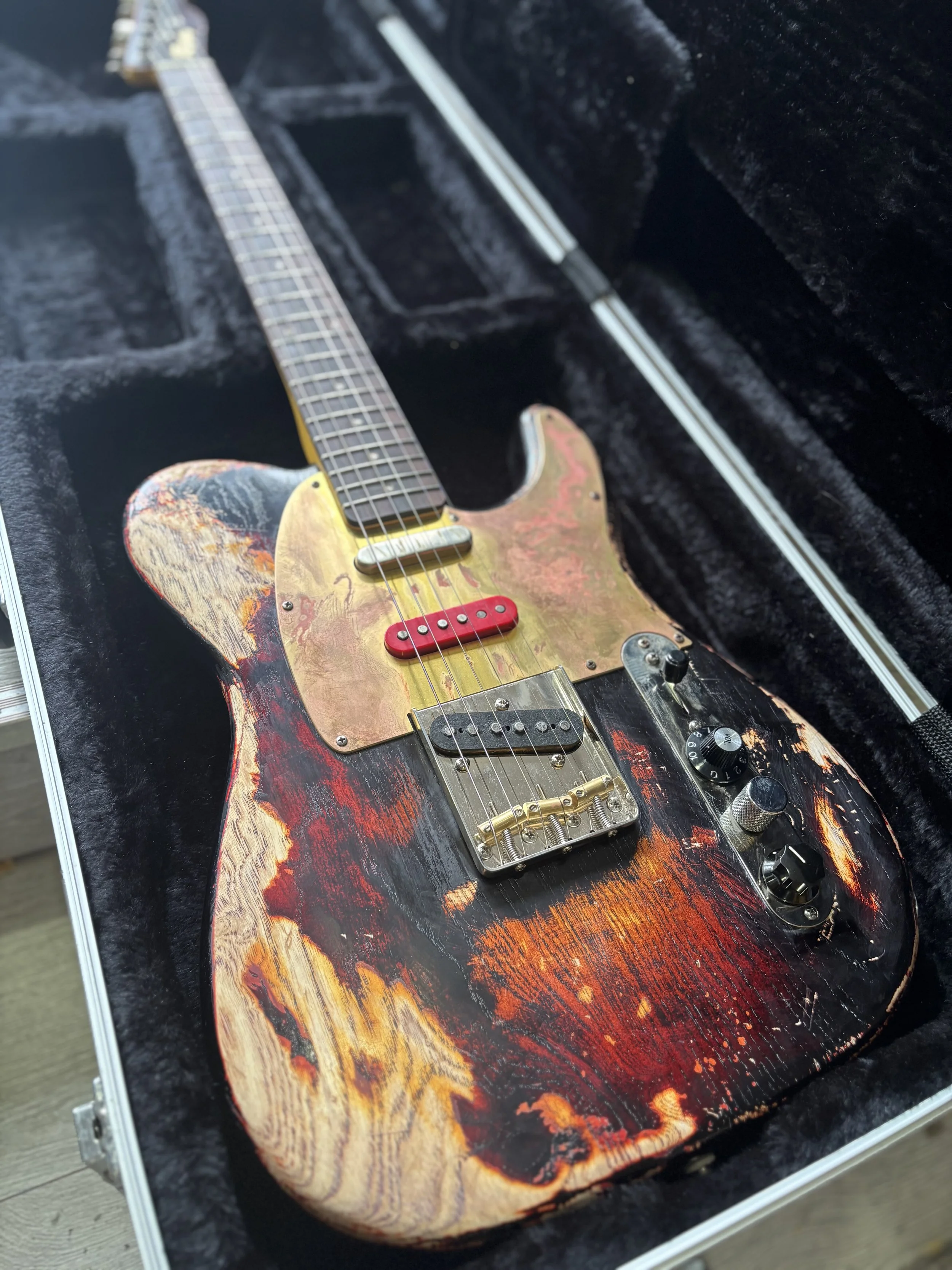heavy reliced brown telecast, gold pickguard, one black, one red and one white pickups, rosewood neck