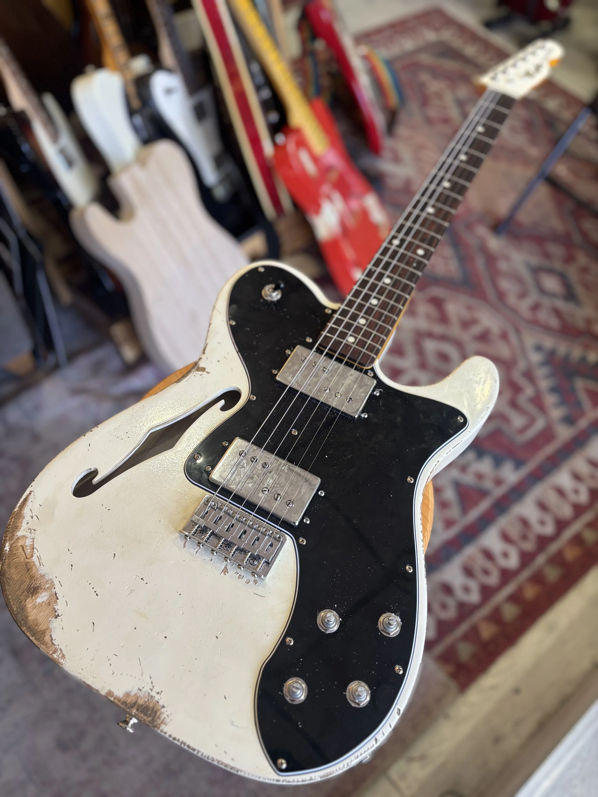 white semi-hollow classic fender style telecaster, HH coil taps, F hole. Rosewood neck and black pickguard