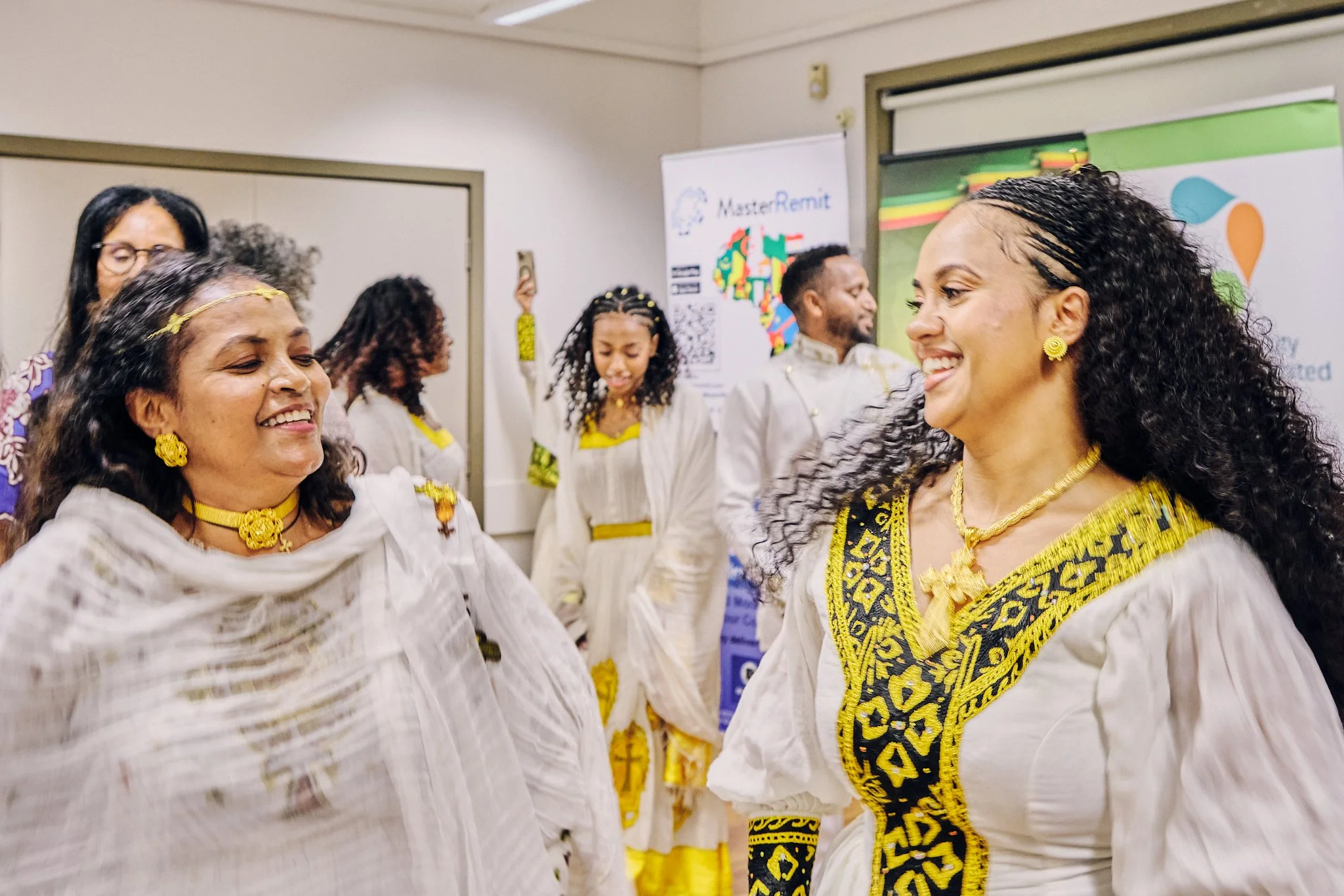 Women and girls from the Ethiopian Community in Sydney Australia dressed in traditional white and yellow clothing, smiling and dancing at the 2025 Ethiopian New Year Celebration.