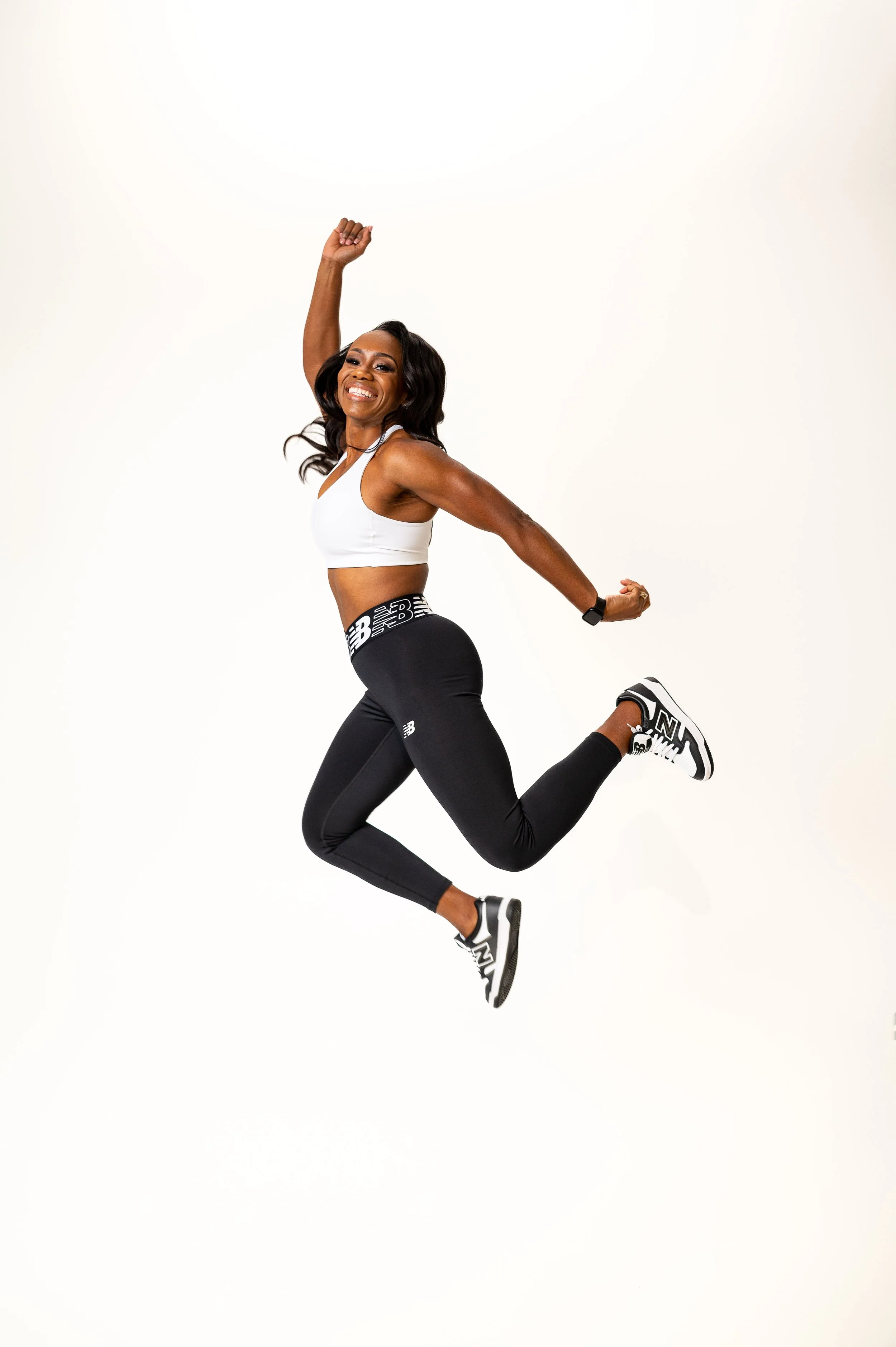 Vanessa Bosse souriante en vêtements de sport sautant dans un fond blanc