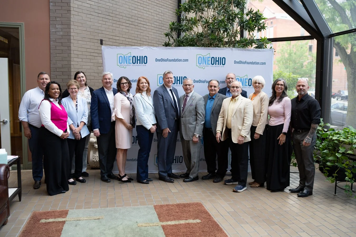 A group of business professionals posing together in front of a One Ohio Recovery Foundation backdrop.
