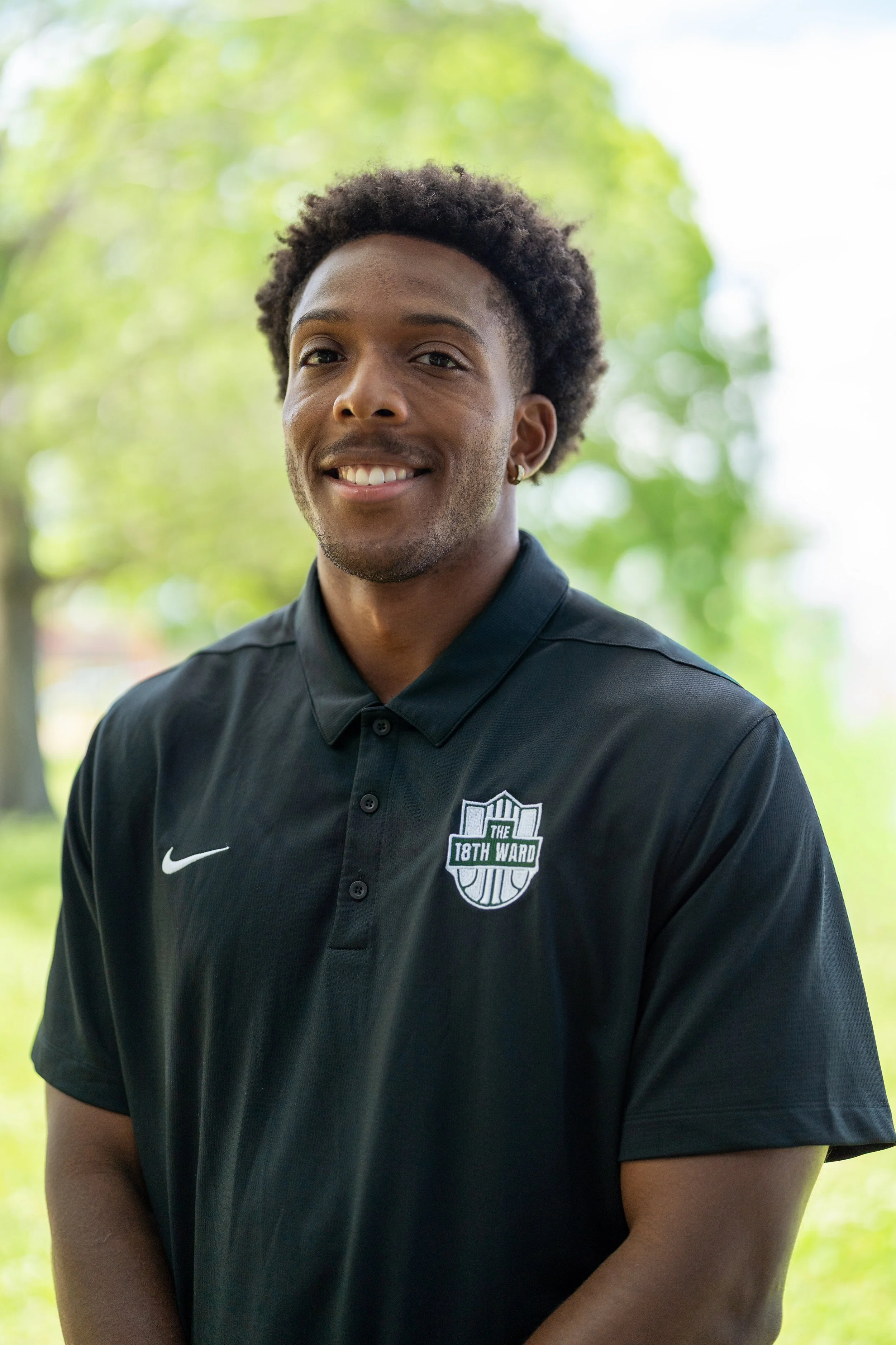 Person smiling wearing a black polo with "18th Ward Sports Club" logo and "Stimulus" emblem.