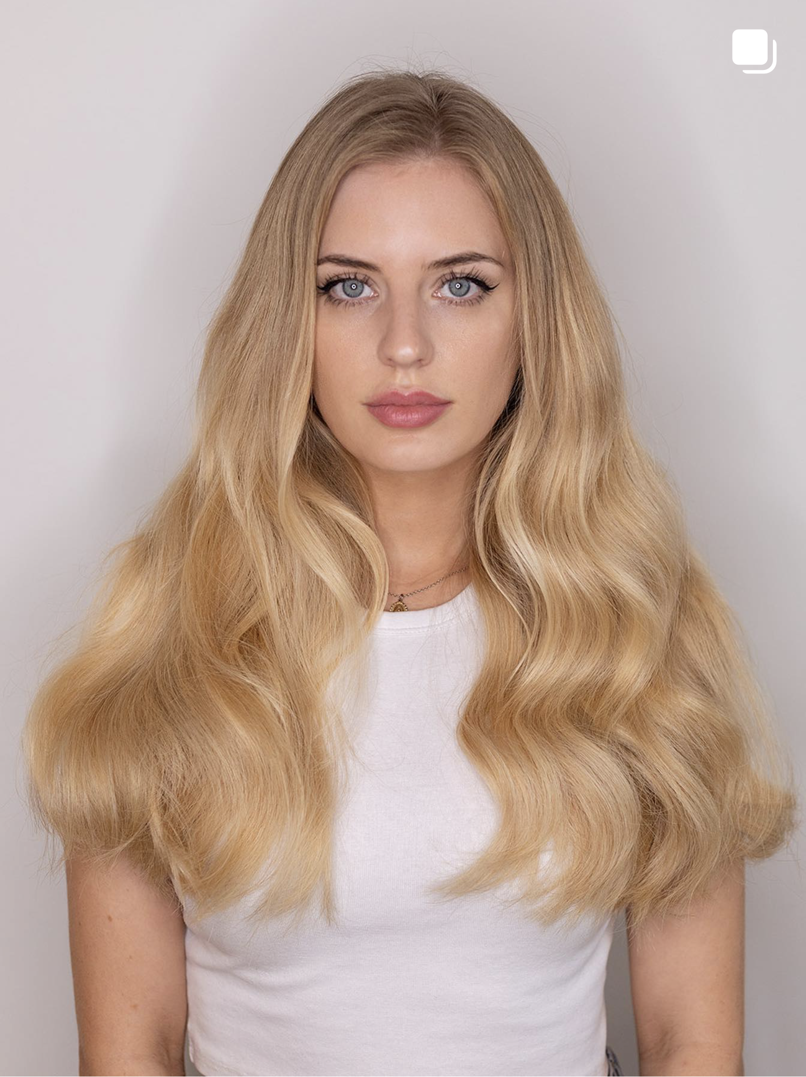 Soft blonde extensions styled with natural volume and movement.