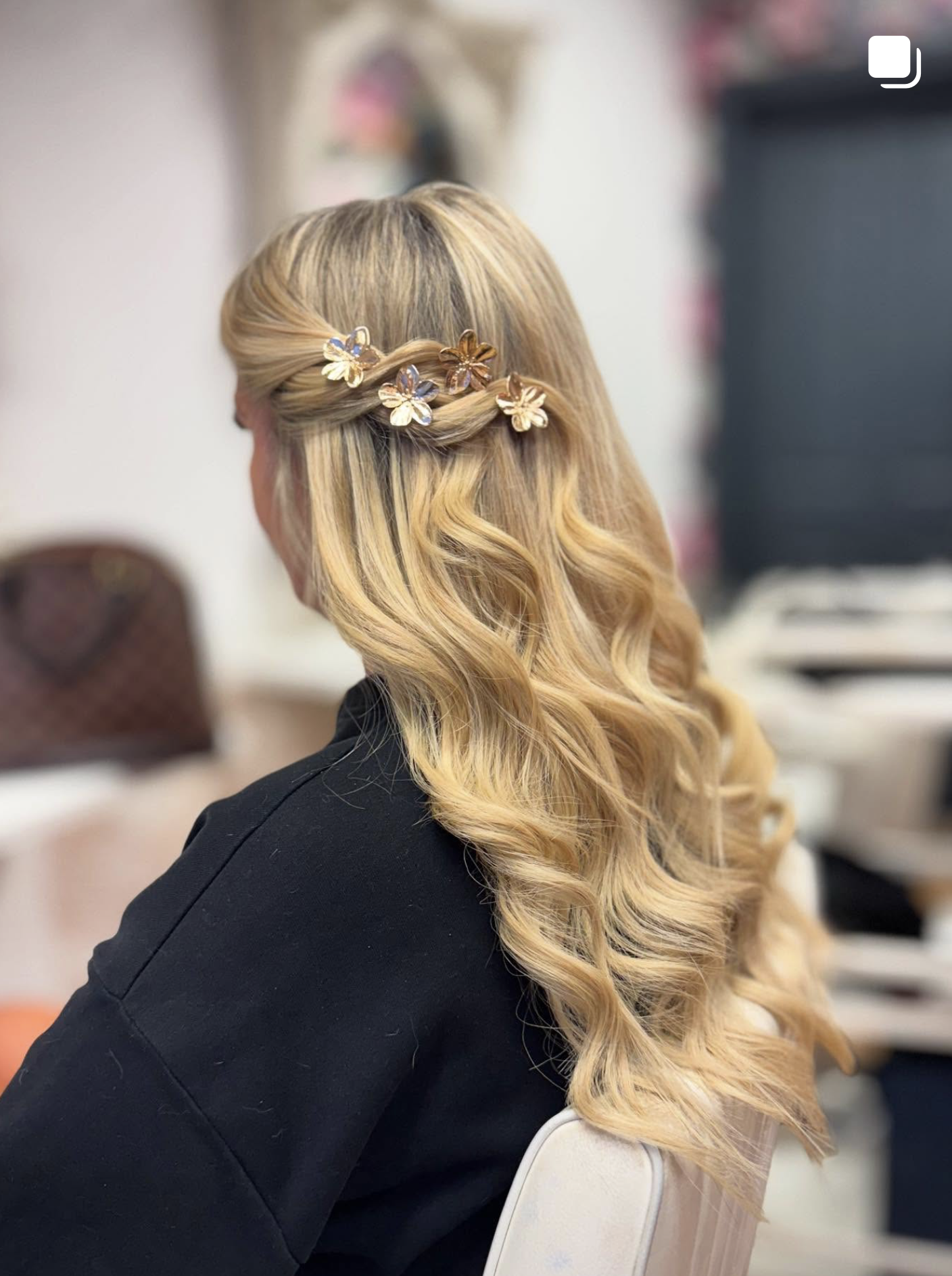 Blonde extensions styled in a soft half-up finish.