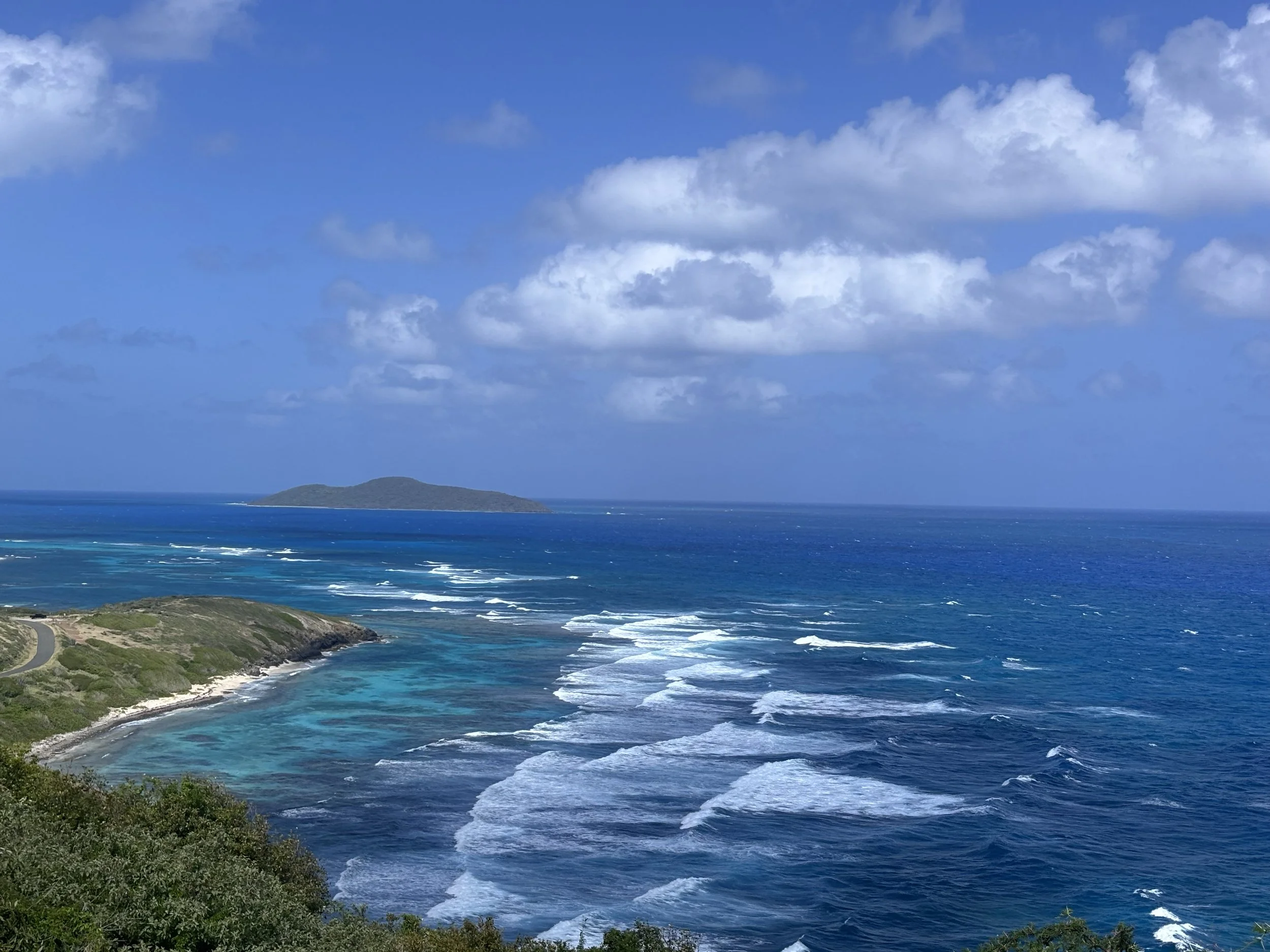 A wide shot of a blue ocean with mountains in the background