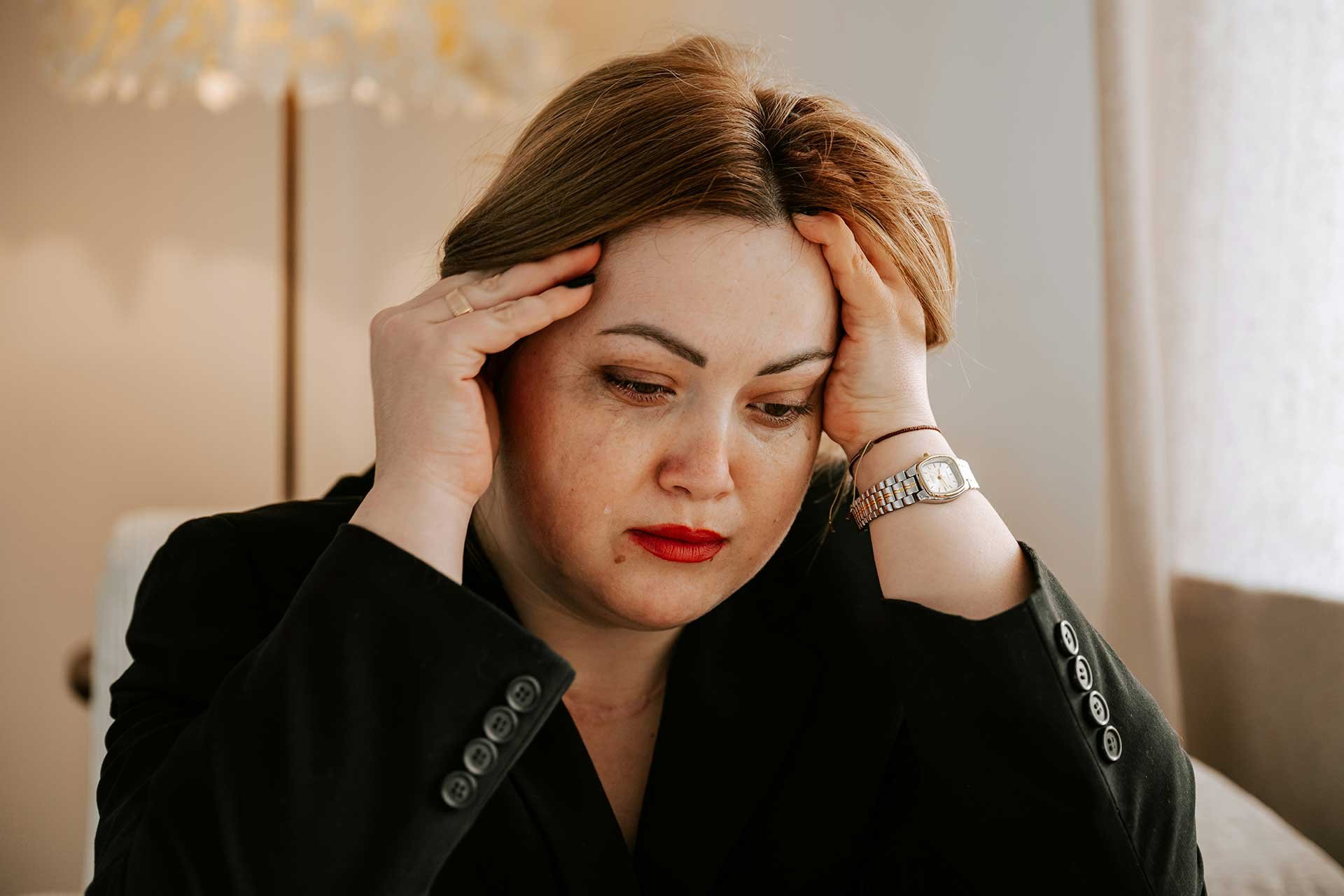 Stressed woman holding her head in her hands and crying as if navigating an overwhelming situation.