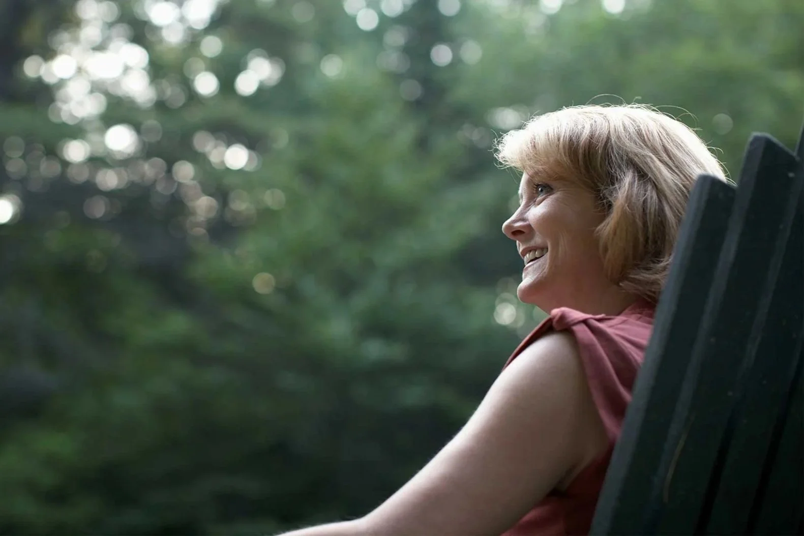 Smiling woman relaxing outdoors, looking up with a confident, hopeful expression