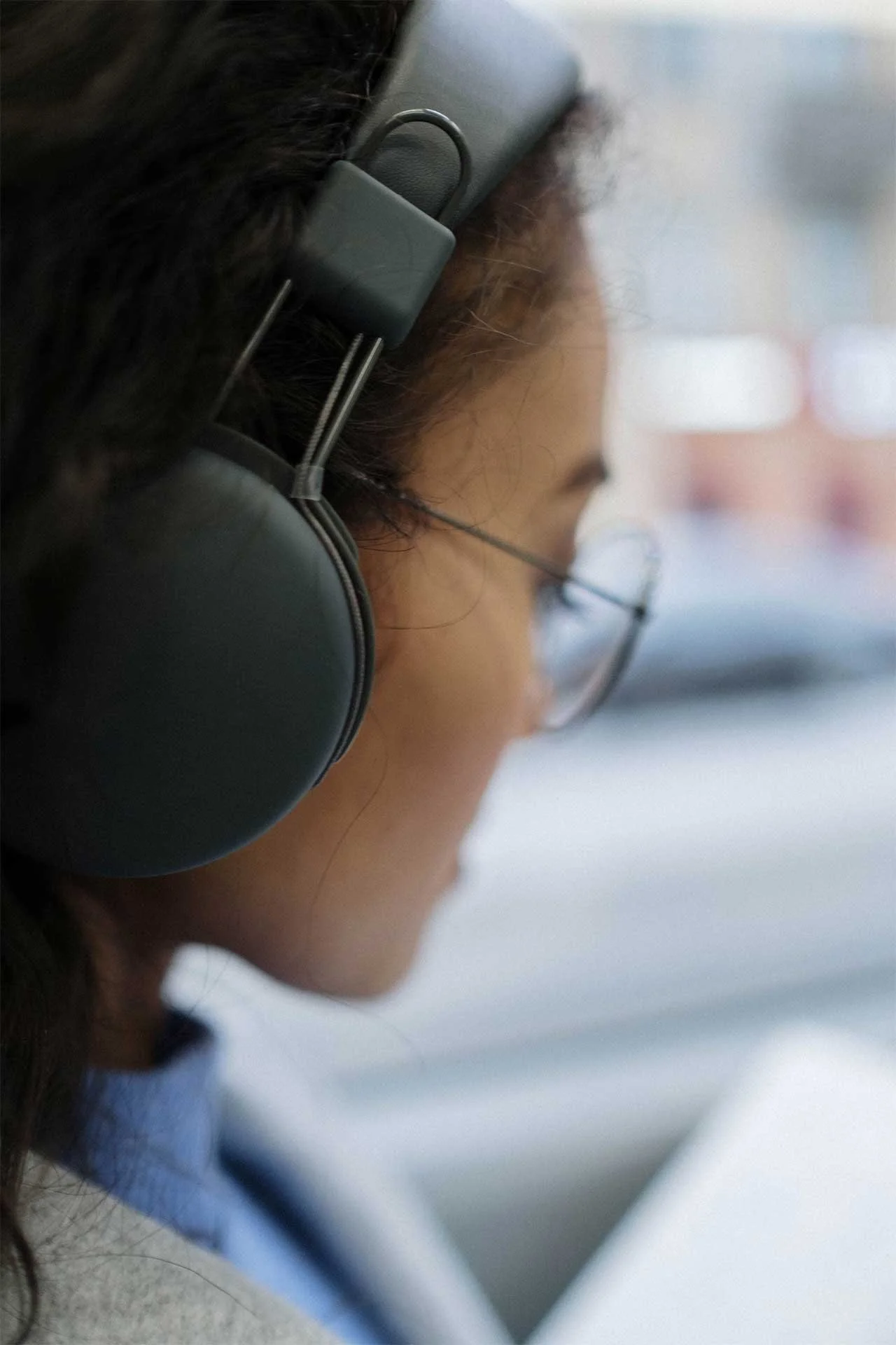 Close-up of a woman wearing headphones, listening attentively to a podcast