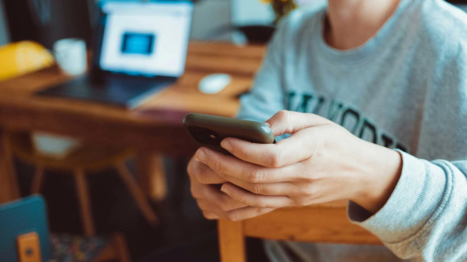 Close-up of a woman wearing a comfortable sweatshirt, using her smartphone