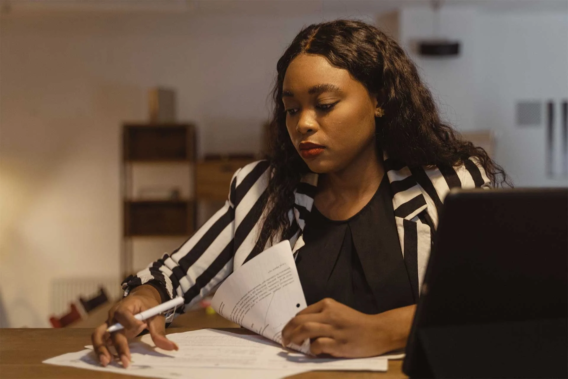 Working woman reviewing and completing paperwork at her desk at night