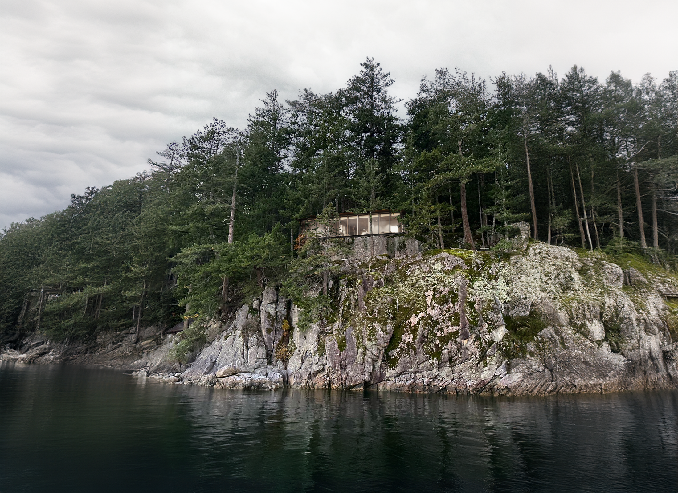 A house perched on a rocky cliff overlooking a body of water with green trees and an overcast sky.