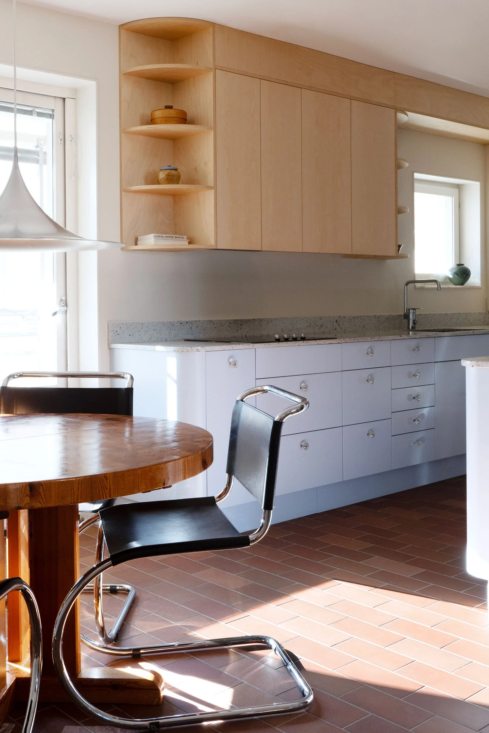 The Pomo Kitchen in Stockholm by Studio Navet — pastel blue cabinetry, natural wood, granite counter, and terracotta tiles in a postmodern apartment.