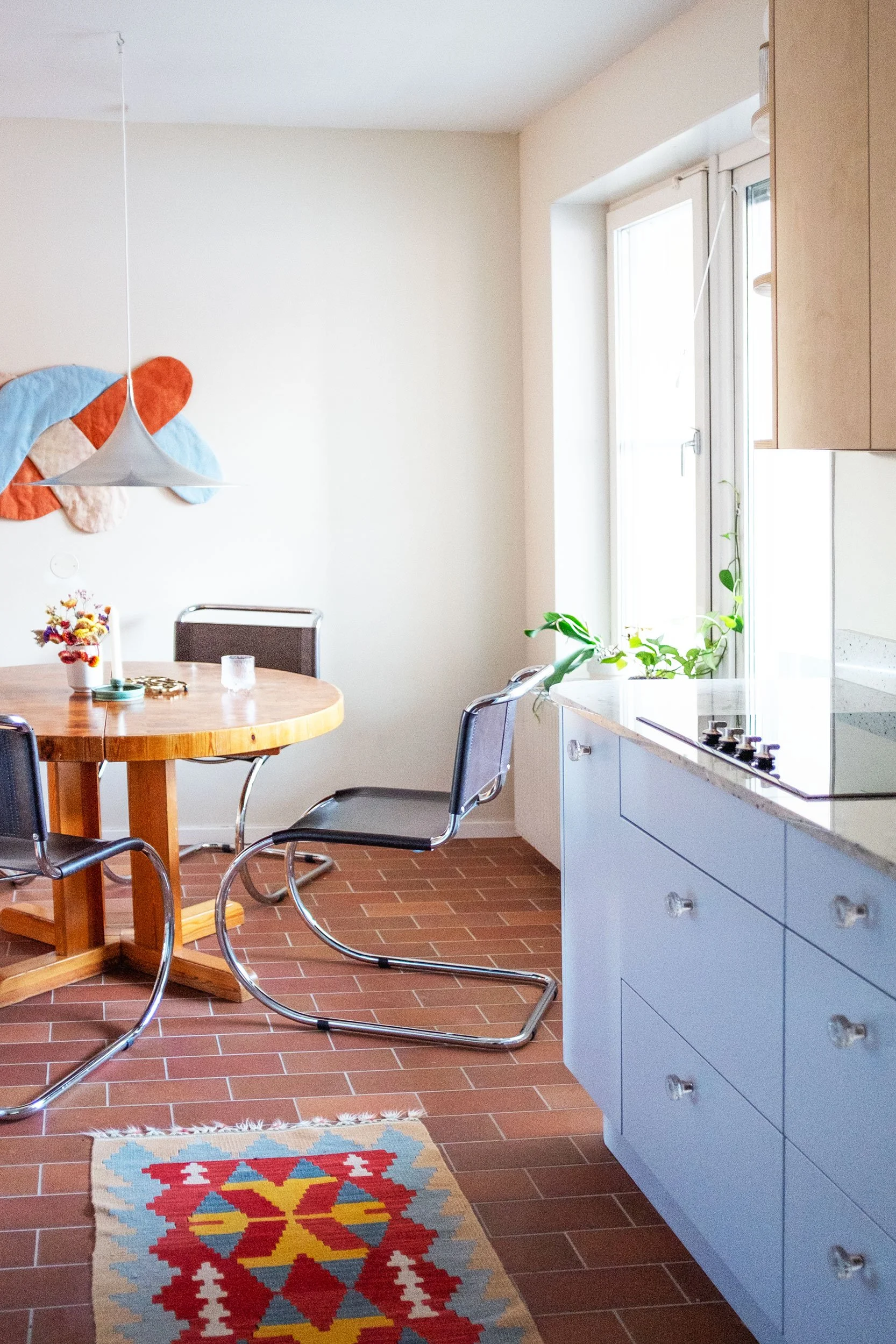 The Pomo Kitchen in Stockholm by Studio Navet — pastel blue cabinetry, natural wood, granite counter, and terracotta tiles in a postmodern apartment.