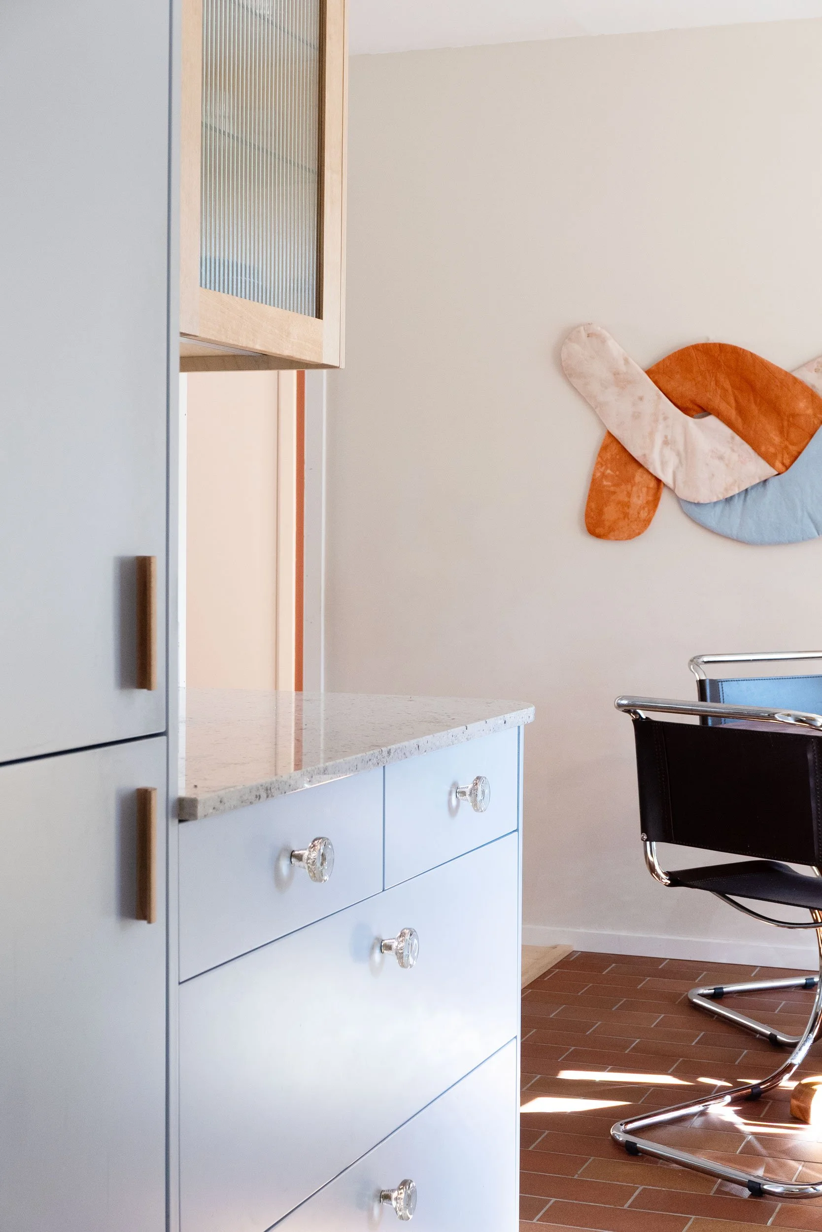 The Pomo Kitchen in Stockholm by Studio Navet — pastel blue cabinetry, natural wood, granite counter, and terracotta tiles in a postmodern apartment.
