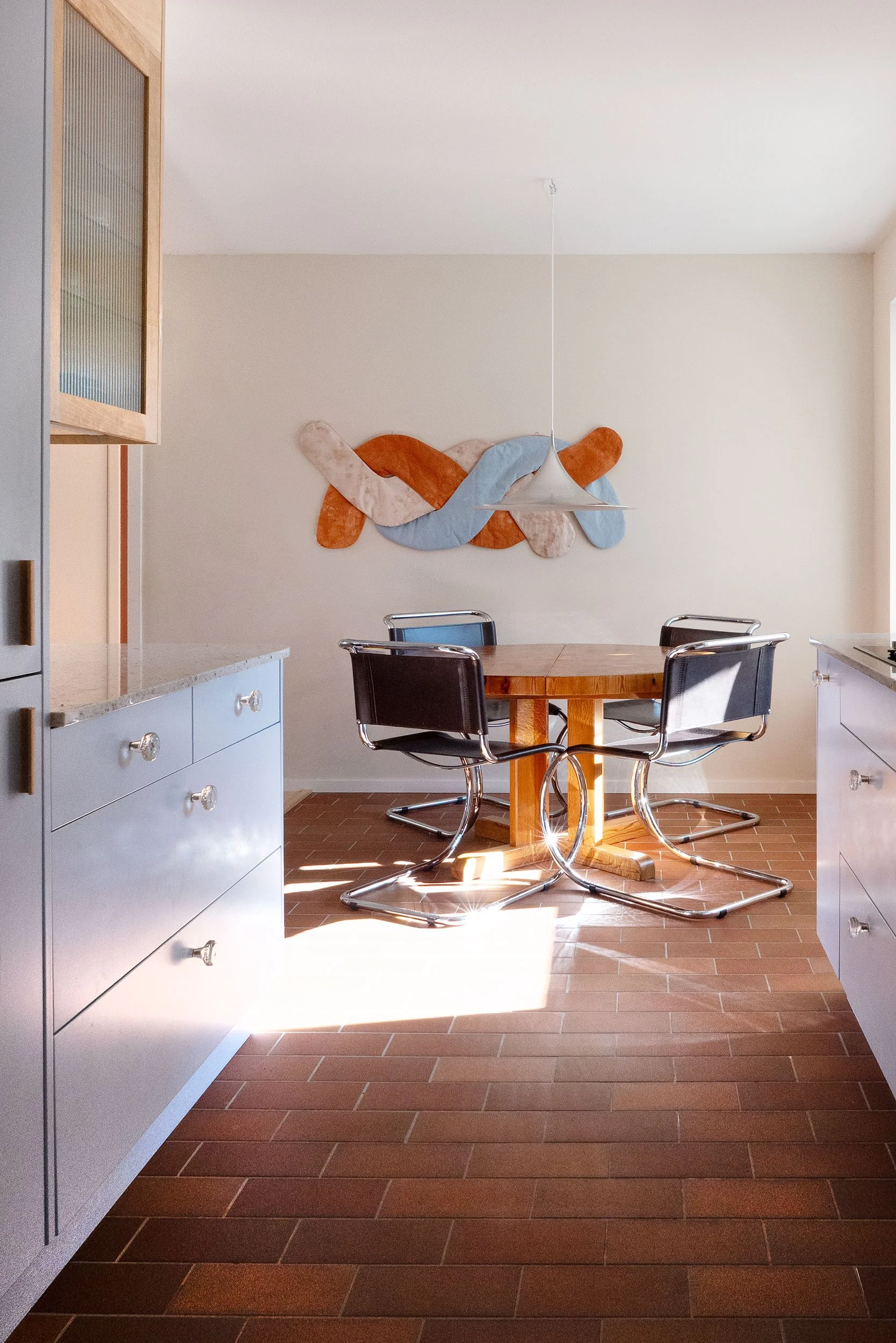 The Pomo Kitchen in Stockholm by Studio Navet — pastel blue cabinetry, natural wood, granite counter, and terracotta tiles in a postmodern apartment.