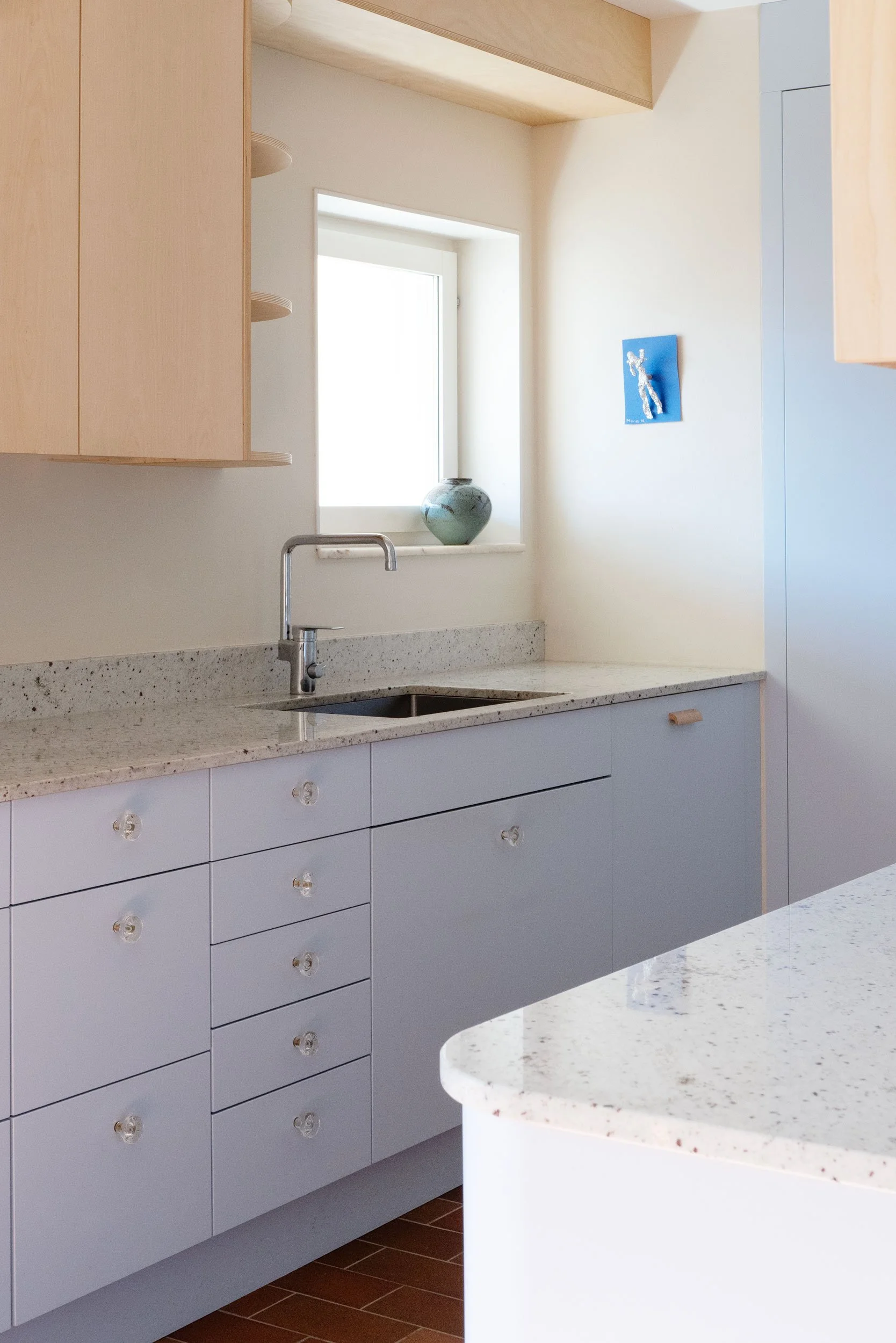 The Pomo Kitchen in Stockholm by Studio Navet — pastel blue cabinetry, natural wood, granite counter, and terracotta tiles in a postmodern apartment.