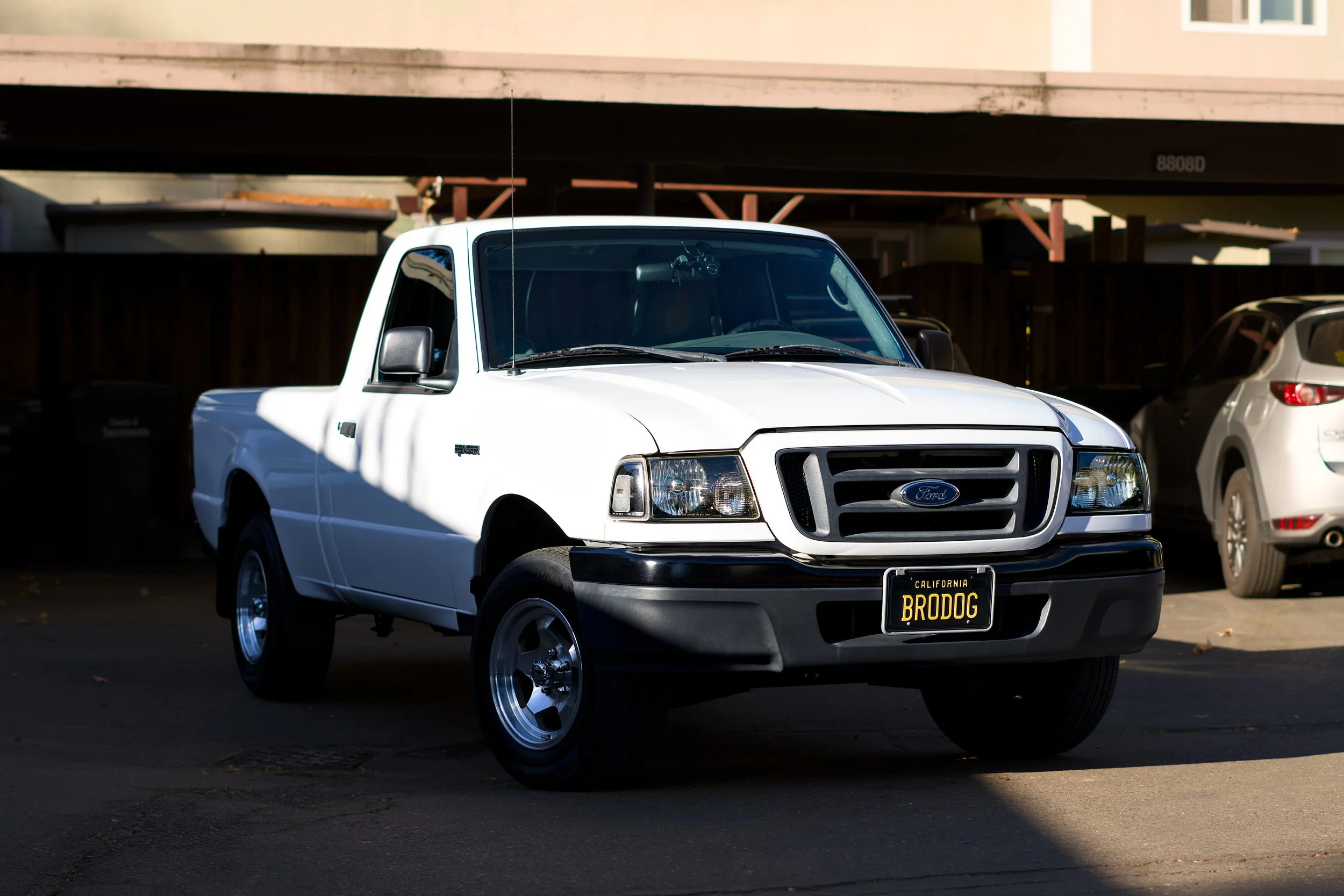 White Ford Ranger with black bumper and California license plate reading 'BRODOG' parked in a lot.