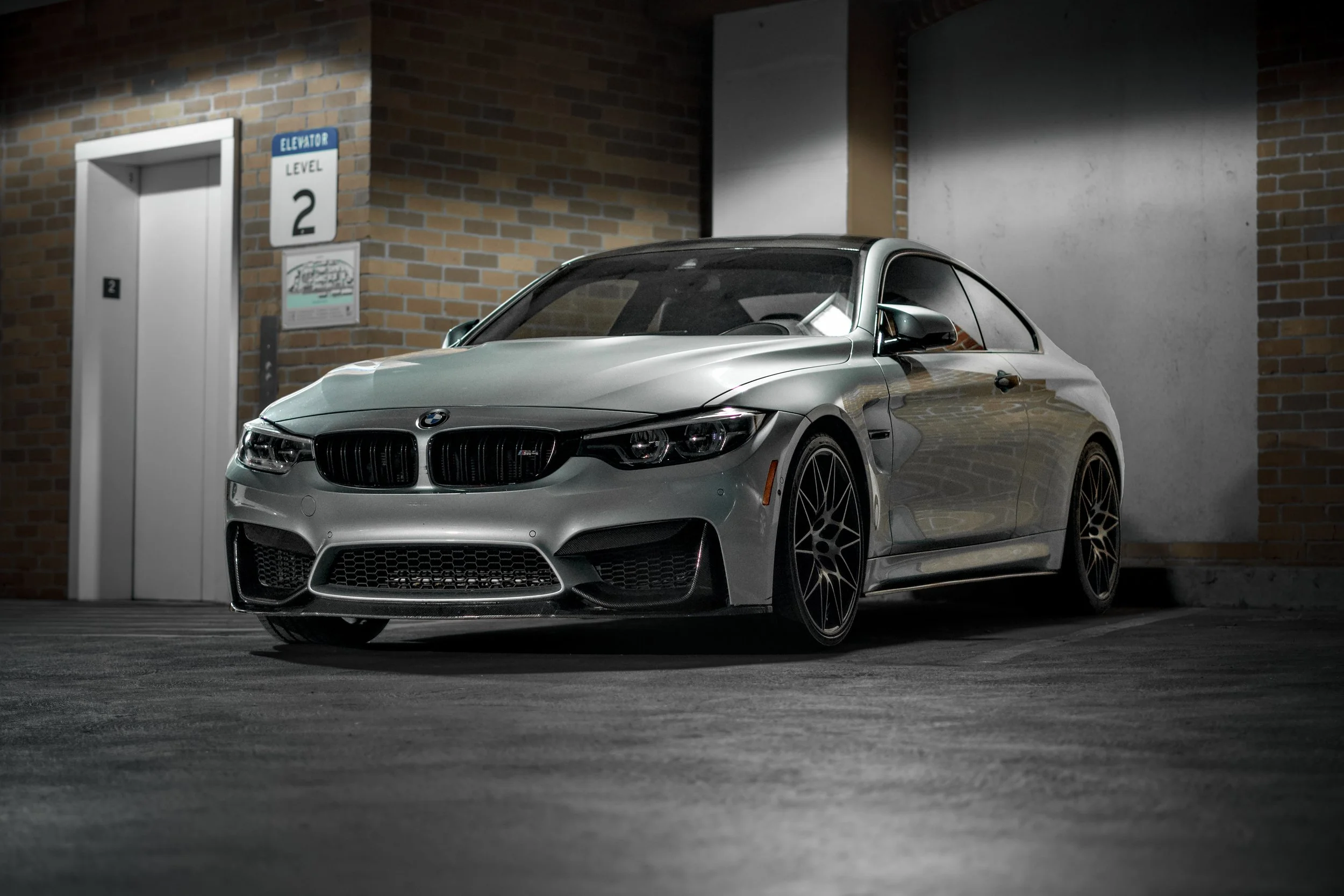 A silver BMW sports car parked in an underground garage near an elevator.