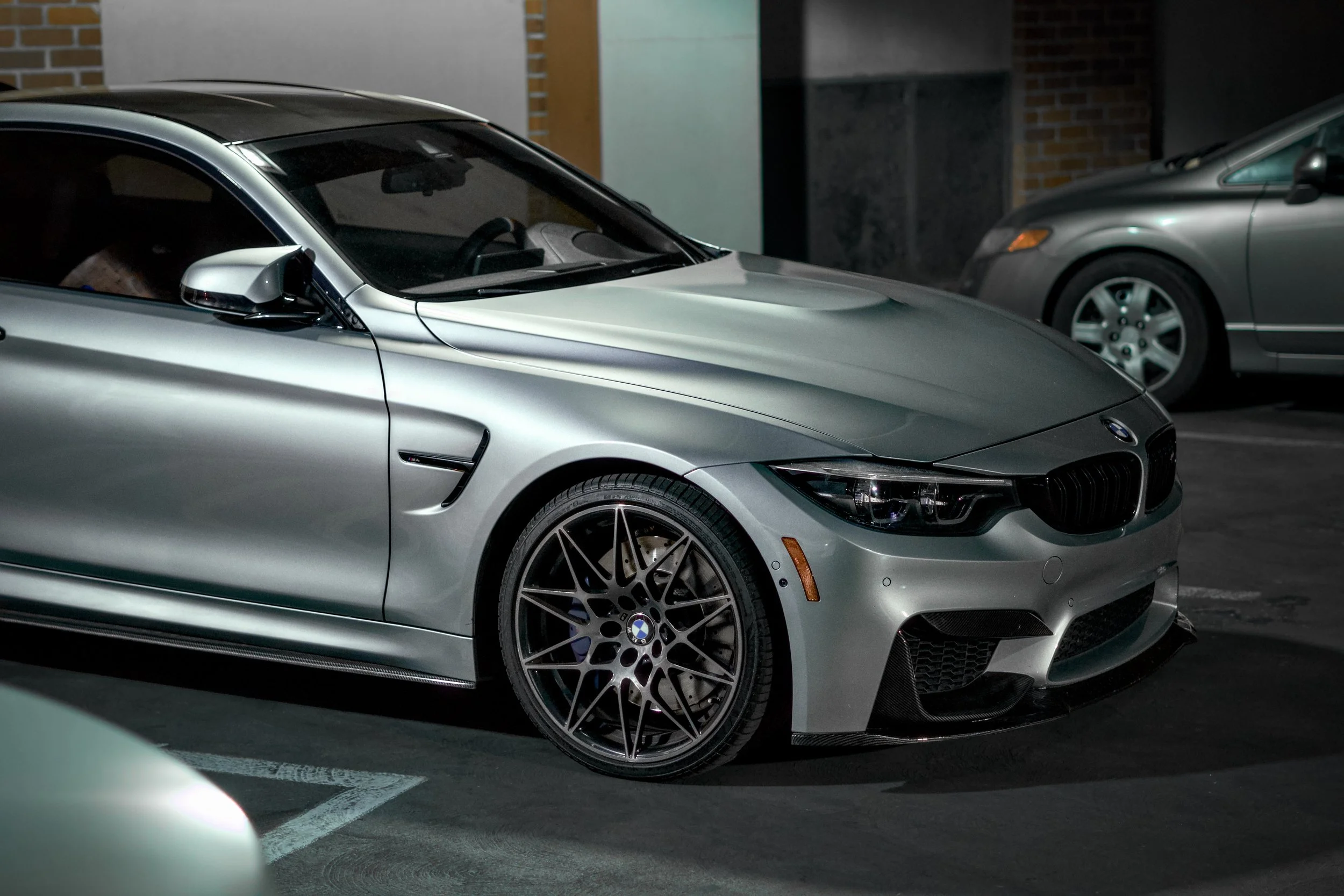 Silver BMW M4 parked in a parking lot at night.