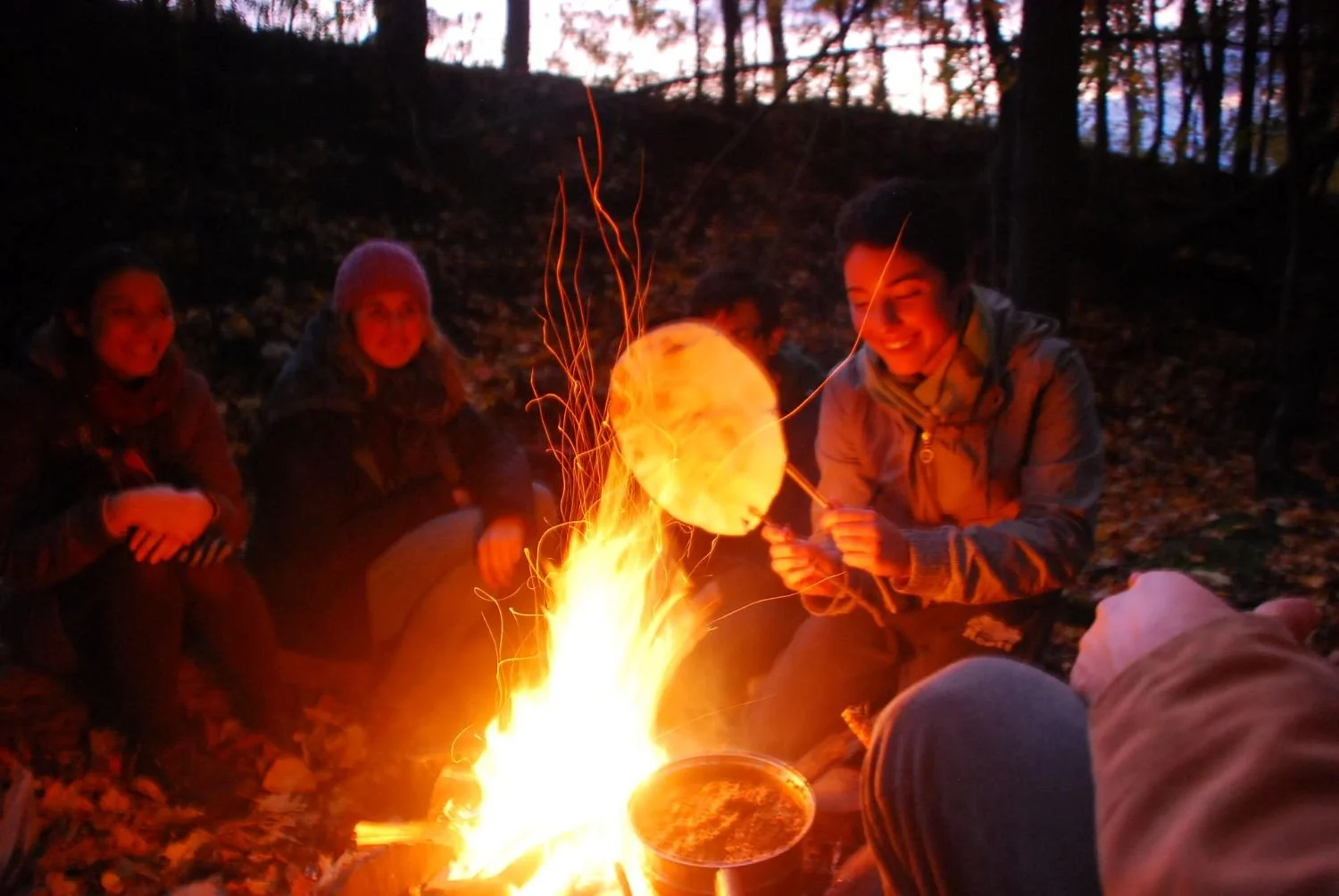 Connecting and sharing food over campfire with friends near Montreal, Quebec