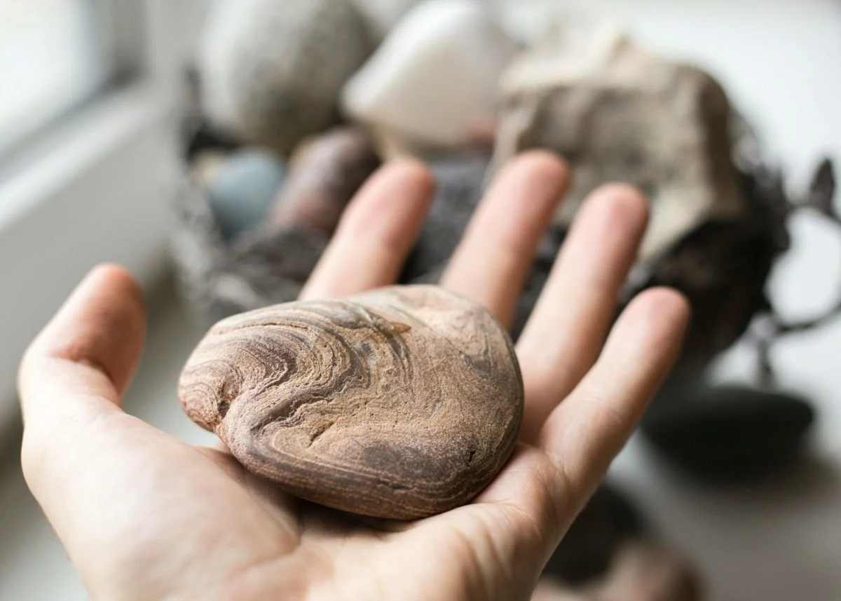 Stone resting in an open palm, symbolising quiet pressure and emotional endurance