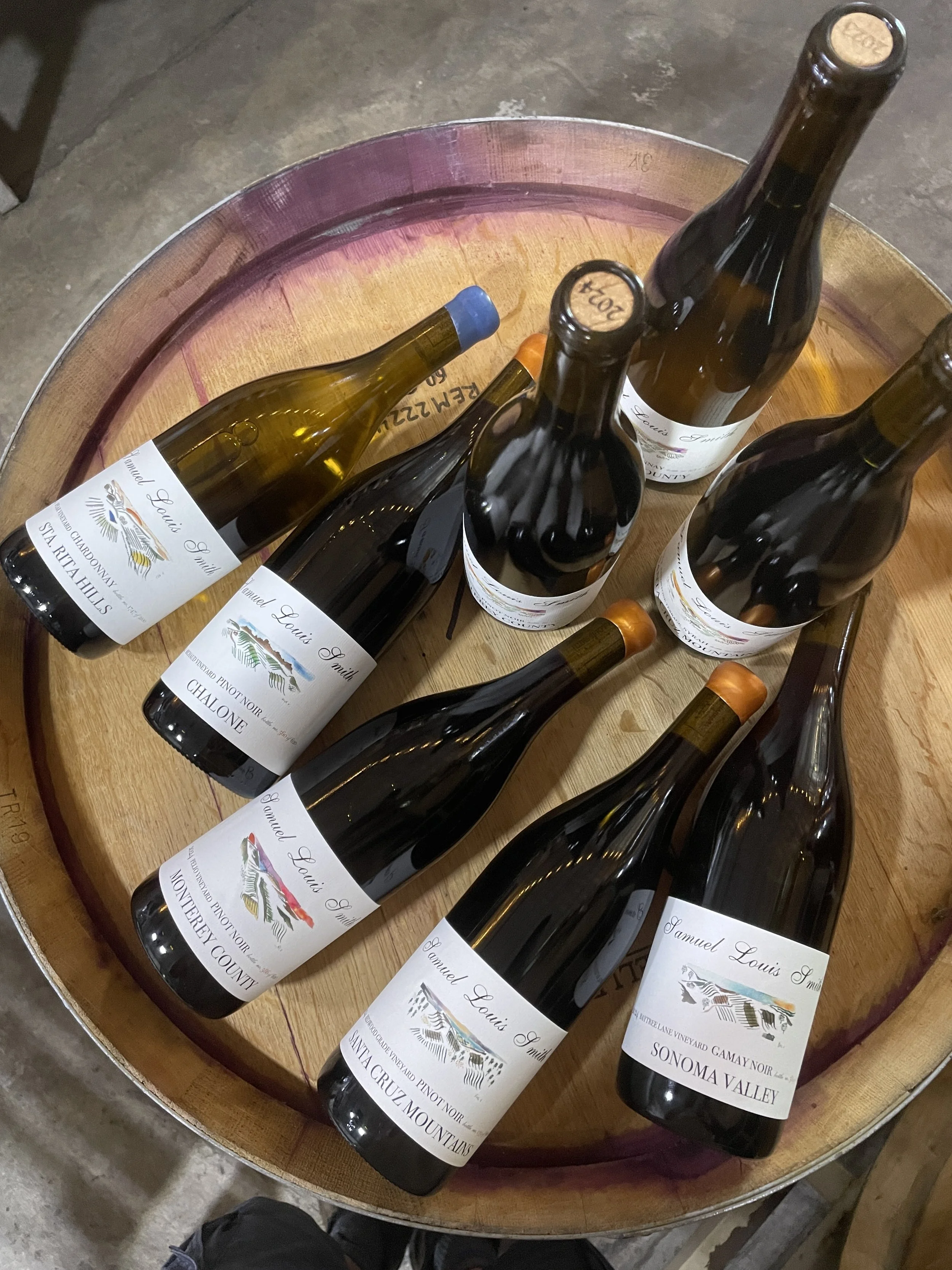 Multiple wine bottles on a wooden barrel.