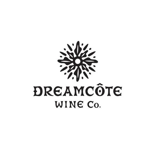 Logo for Dreamcôte Wine Company featuring a stylized sun or flower design in black and white.