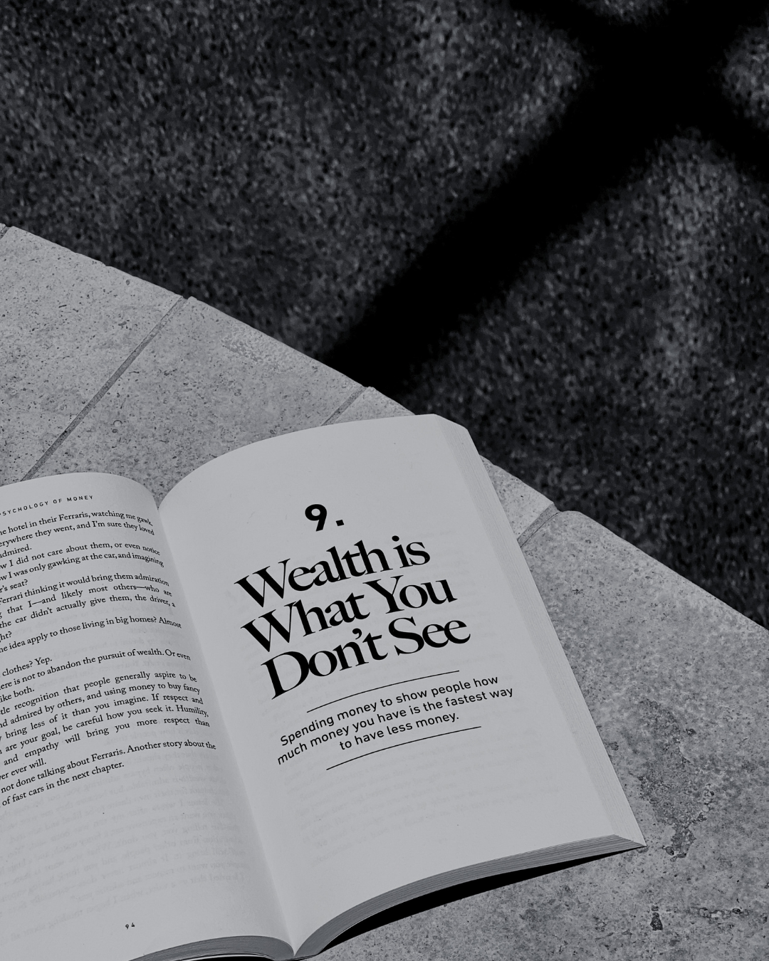 Open magazine on a stone surface with the title 'Wealth is What You Don't See' and a subtitle about spending money to appear wealthier.