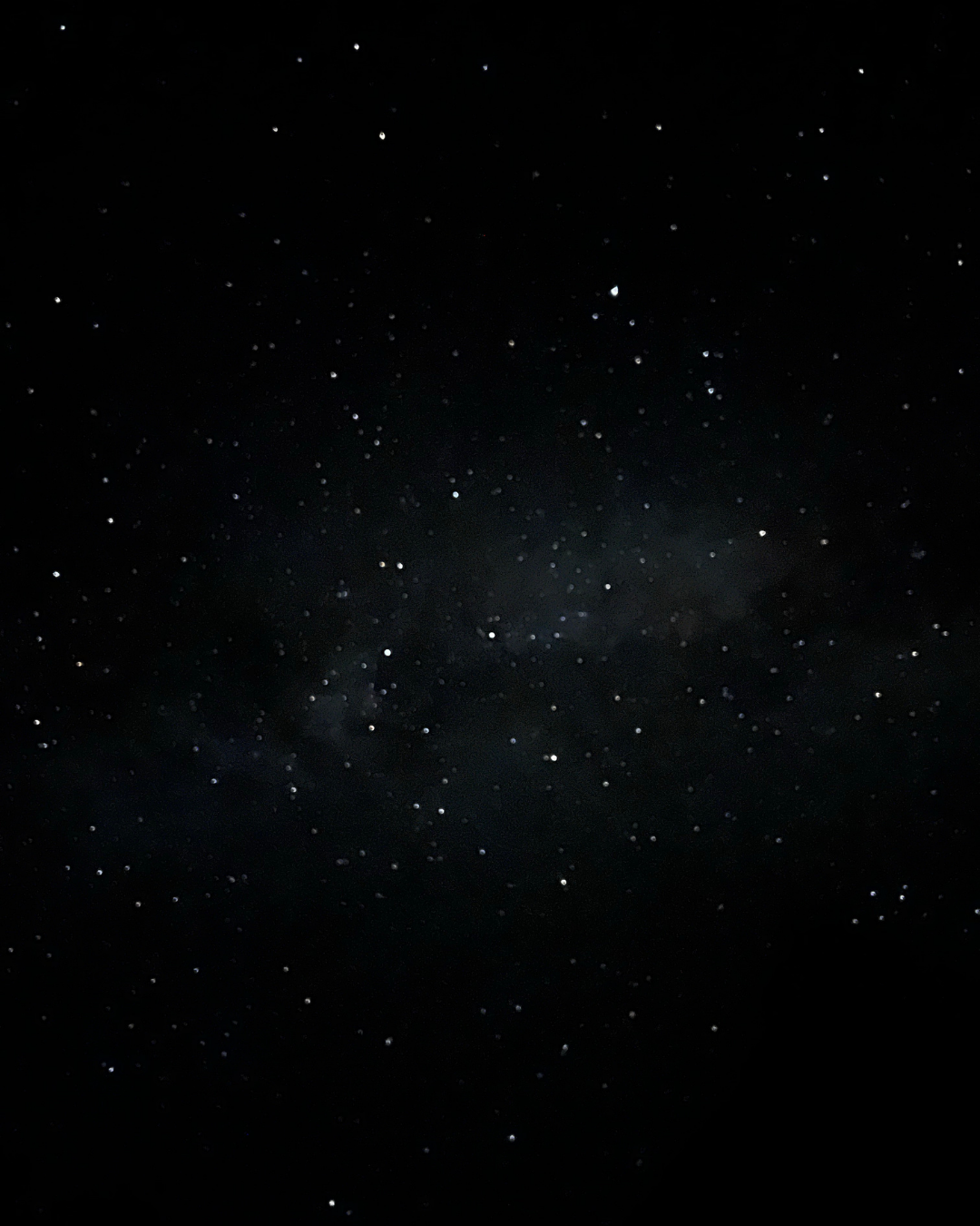 A clear night sky filled with numerous stars and a faint view of the Milky Way galaxy.