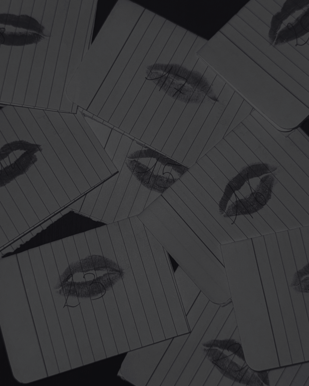 Scattered paper sheets with printed lips and lines, some overlapping, on a dark surface.