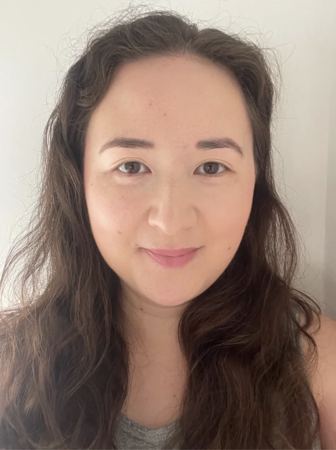 Smiling person with long brown hair and a grey top