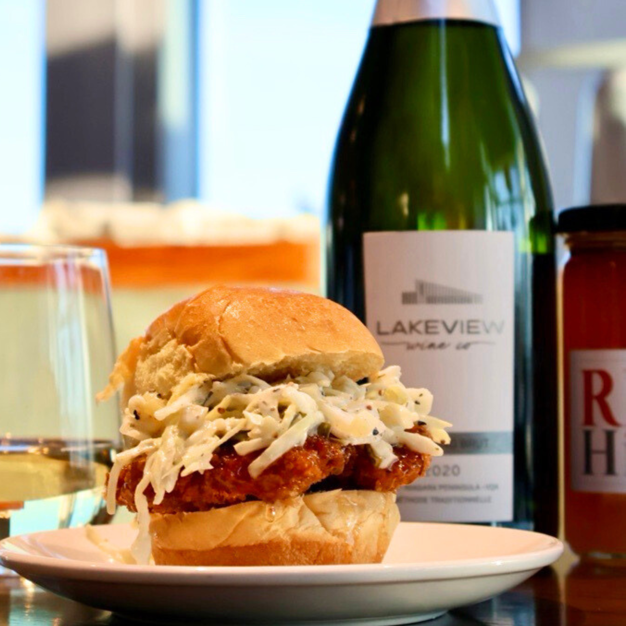 Lakeview Wine Co. Vidal Icewine bottle beside a small plate with a savory dish topped with chopped vegetables and drizzled with white sauce.