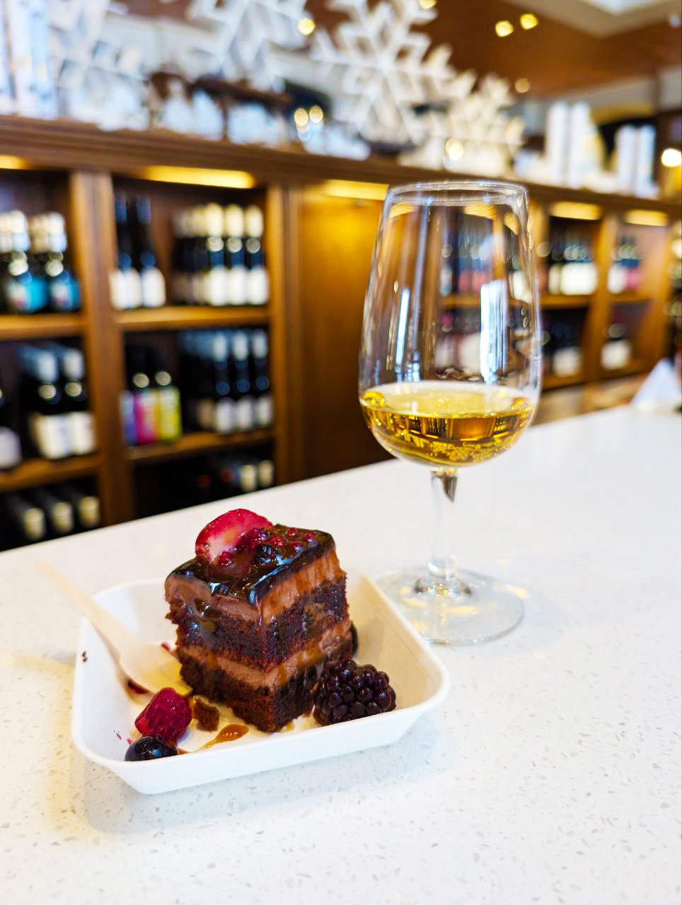 Two bottles of Reif Estate Vidal Icewine with glasses of the wine, paired with a roasted pork sandwich on a small wooden stand