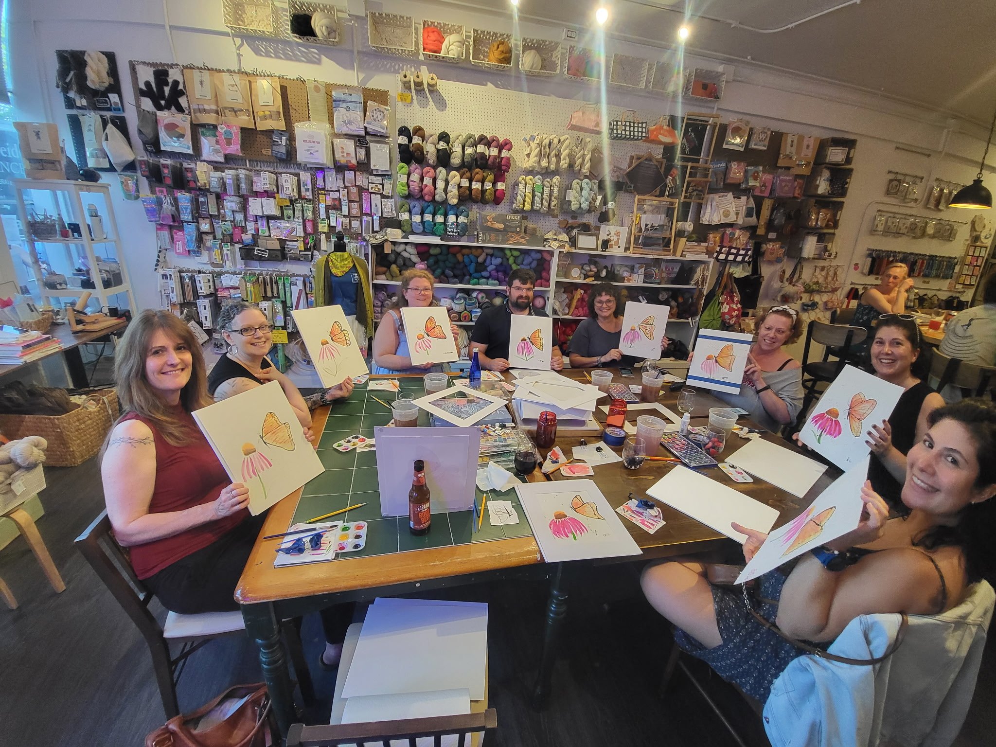 smiling women holding watercolor paintings