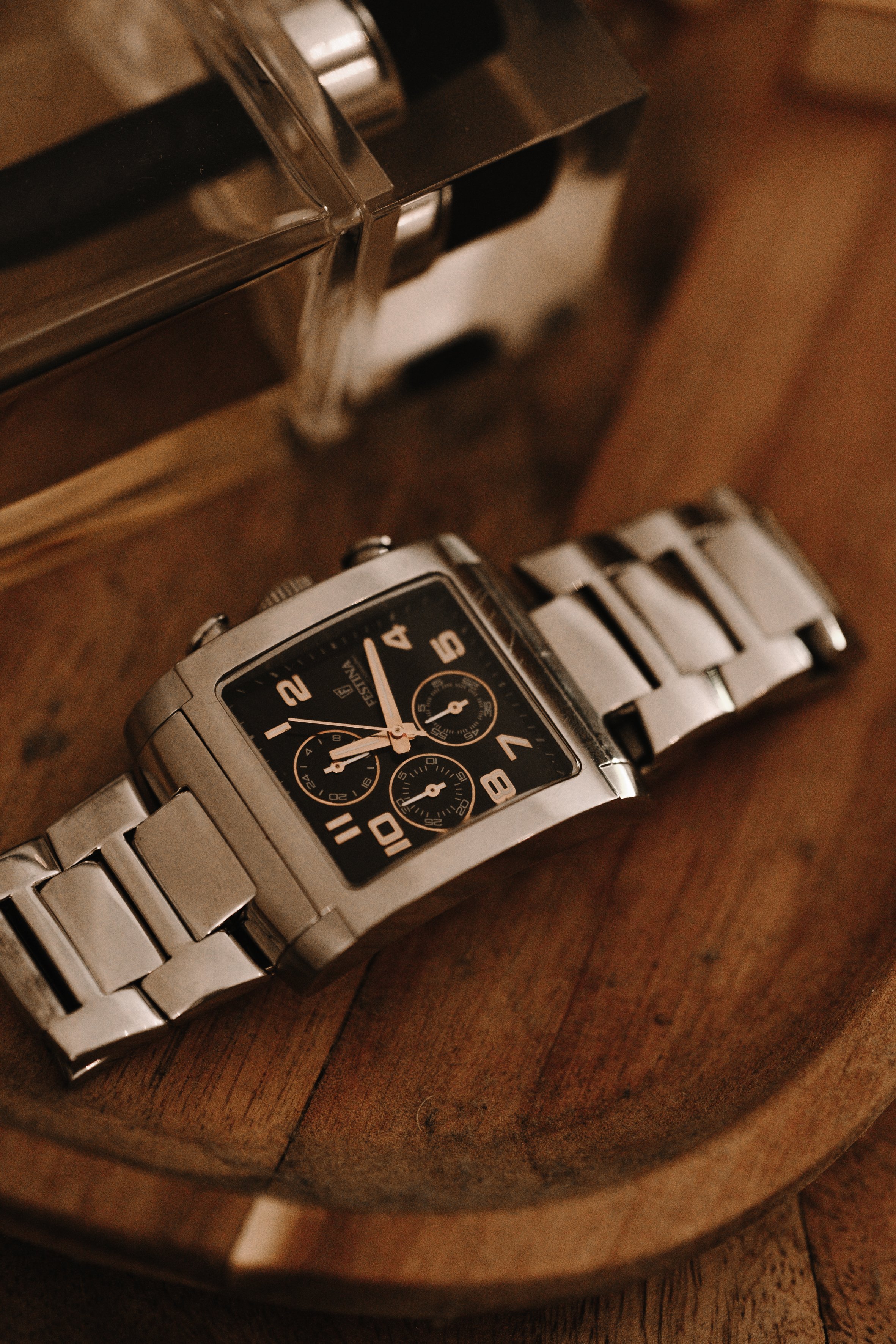 Montre-bracelet en métal sur un plateau en bois.
