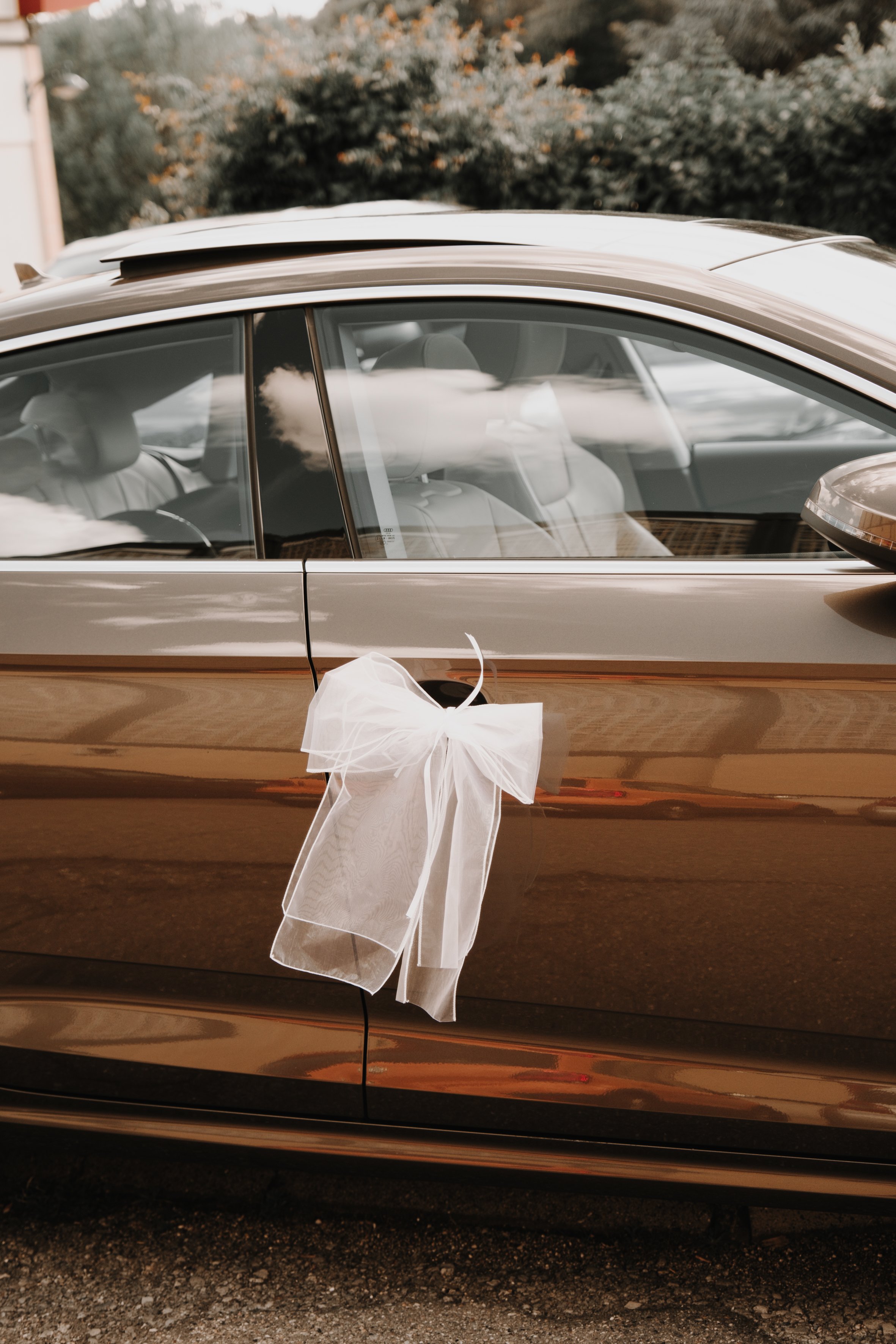Voiture marron avec un nœud blanc sur la poignée de porte.